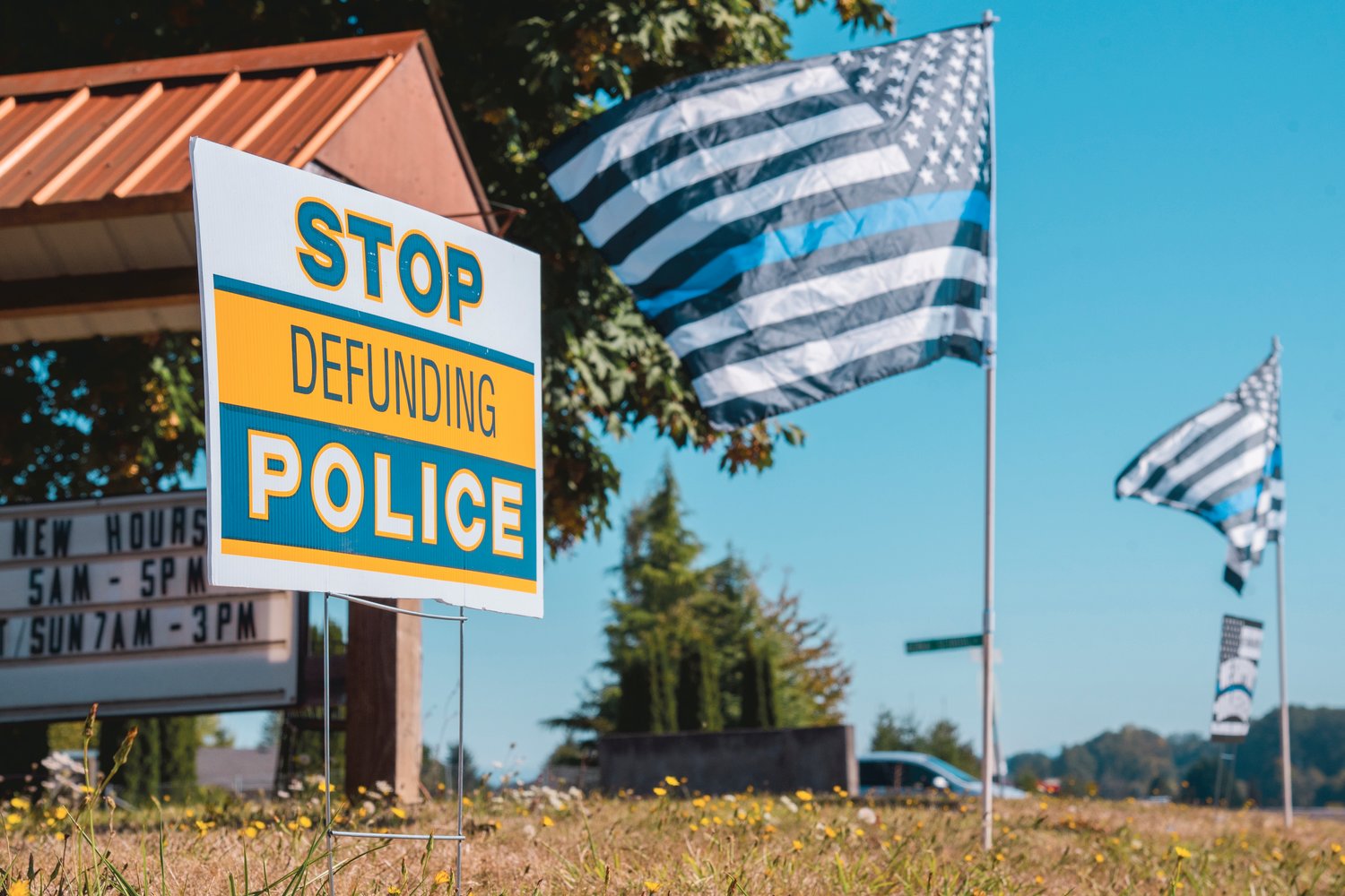 A sign reads “Stop Defunding Police.” It was displayed next to Thin Blue Line flags in Adna on Saturday.