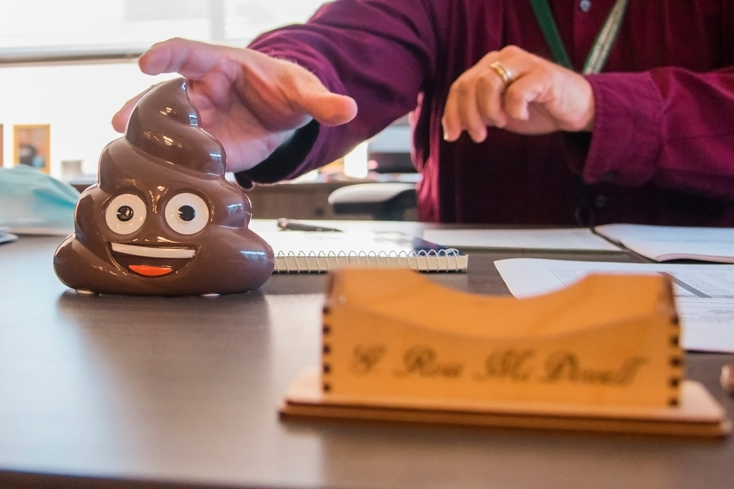 Ross McDowell reaches for a poop emoji coin bank that doubles as a paperweight in his office at the Historic Lewis County Courthouse in Chehalis.