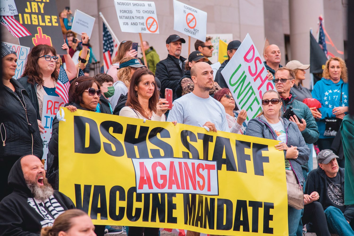 Washington Department of Social and Health Services employees against the vaccine mandate stand and hold signs alongside other rally goers on the steps of the Washington State Capitol Building in Olympia on Sunday.