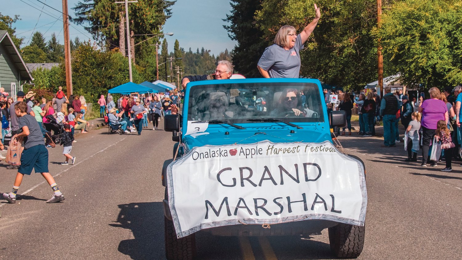 Smiles and waves are exchanged as the Onalaska Apple Harvest Festival Grand Marshal rolls through town during a parade Saturday morning.