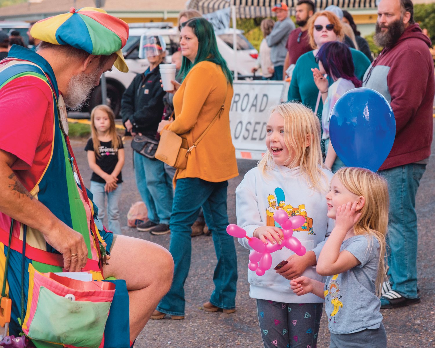 Kids smile after recieving a balloon creation from Ken Trombley, a balloon artist known as the BaLunatic, during the Onalaska Apple Harvest parade.