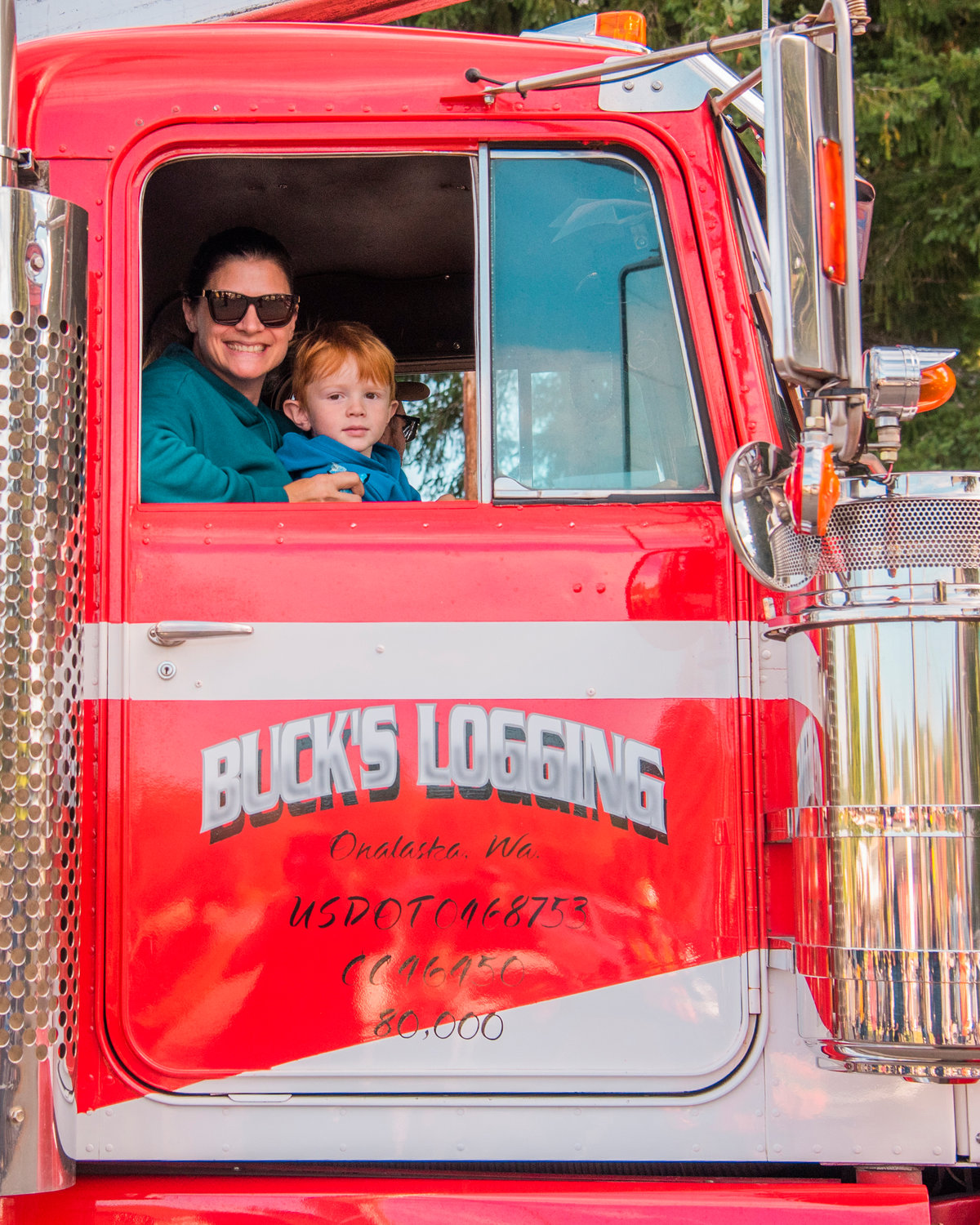 Riders in a Buck’s Logging truck smile for a photo during the Onalaska Apple Harvest parade Saturday morning.