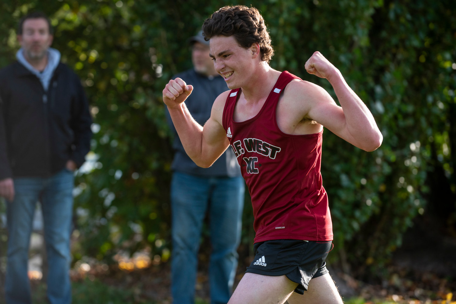 W.F. West's Henry Jordan flexes after crossing the finish line in third place at a three-team meet at Stan Hedwall Park on Wednesday, Oct. 6, 2021.