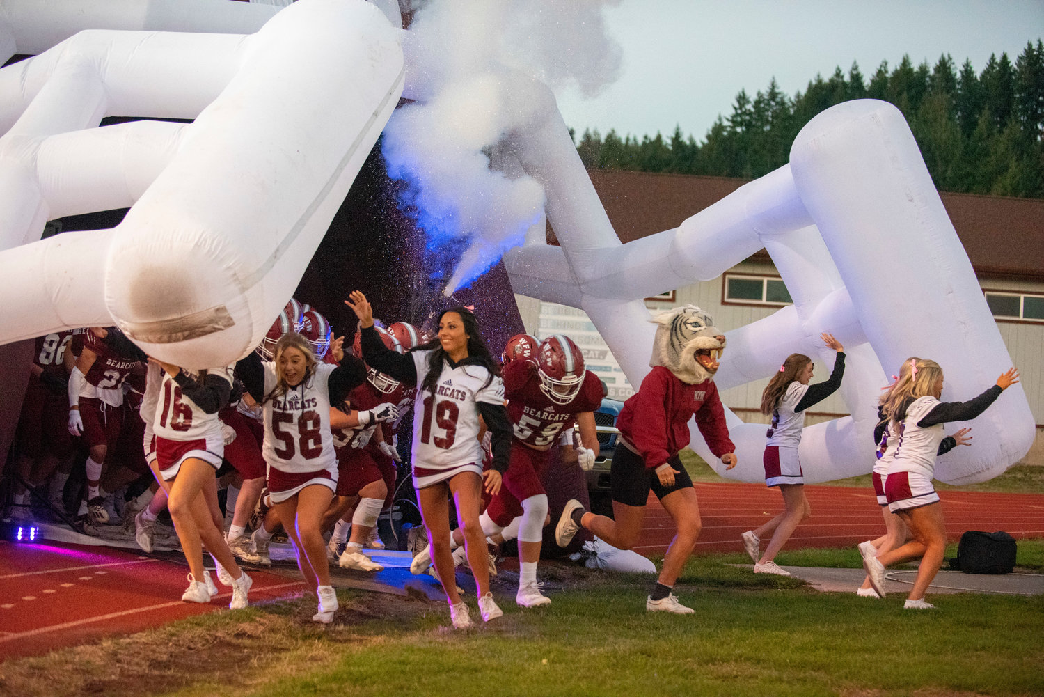 W.F. West football and cheerleaders rush out of their giant Bearcats helmet at the start of their matchup at home with Rochester on Oct. 8, 2021.