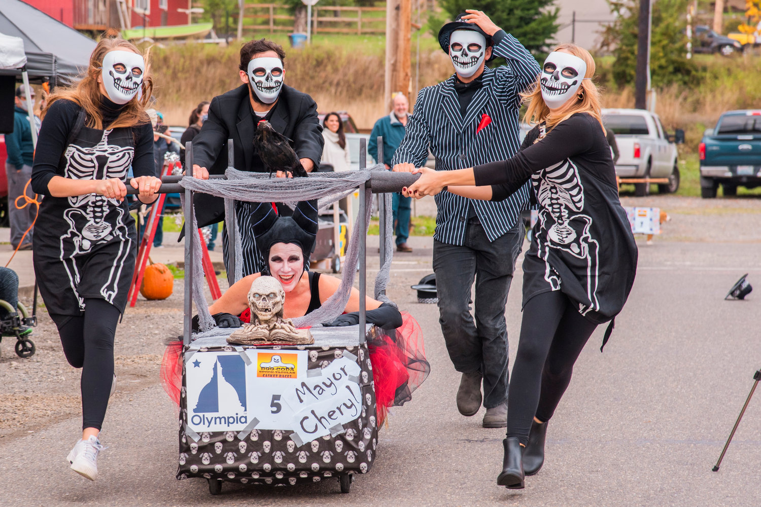 Olympia Mayor Cheryl Selby, laughs while riding in a pine box dressed as Maleficent, along with her City of Olympia crewmates during the Casket Race event outside Boo-coda Town Hall Saturday afternoon.