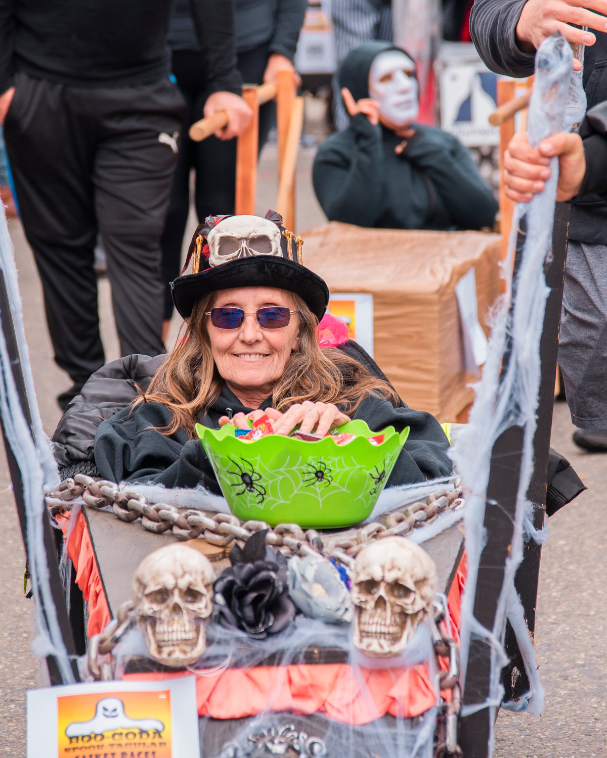 Robin Greene, with Joe’s Place, smiles while holding a bucket of candy in a pine box during the Casket Parade before taking first in the Casket Races event on Saturday.