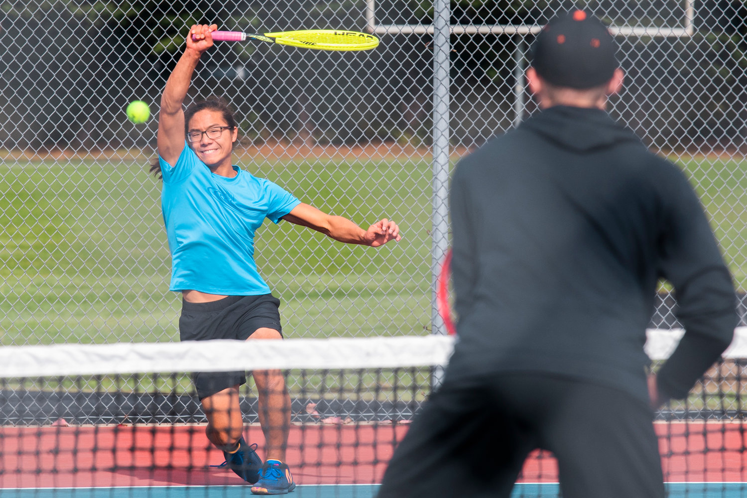 W.F. West’s Joseph Chung smiles as he returns a shot during a doubles match at Black Hills High School Tuesday afternoon.