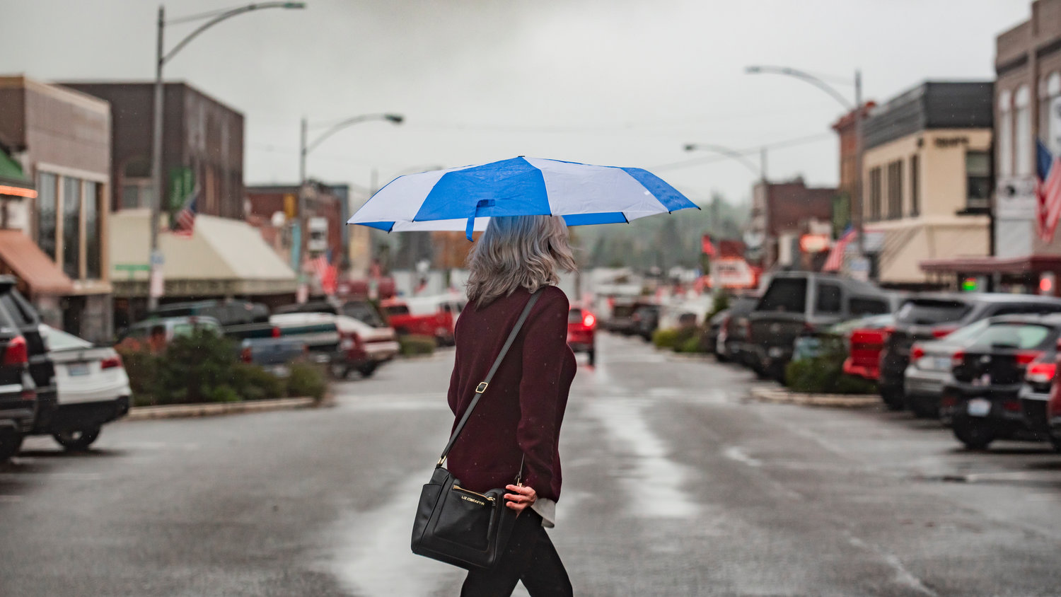 A woman uses an umbrella as she crosses North Market Boulevard as rain falls in Chehalis on Friday.