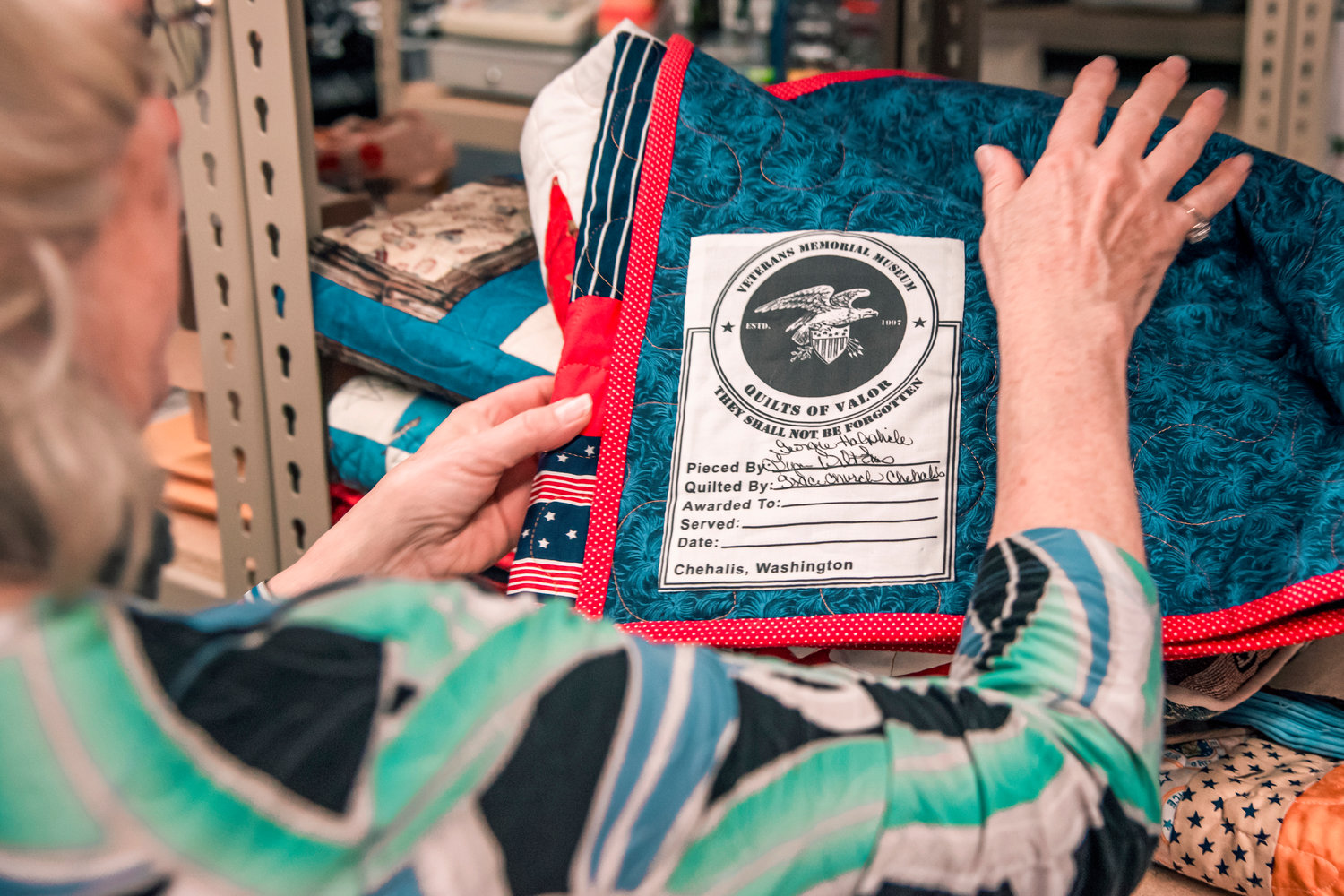 Debbie Aust talks about the label sewn onto every Quilts of Valor piece before being given to Veterans at the Veterans Memorial Museum in Chehalis.