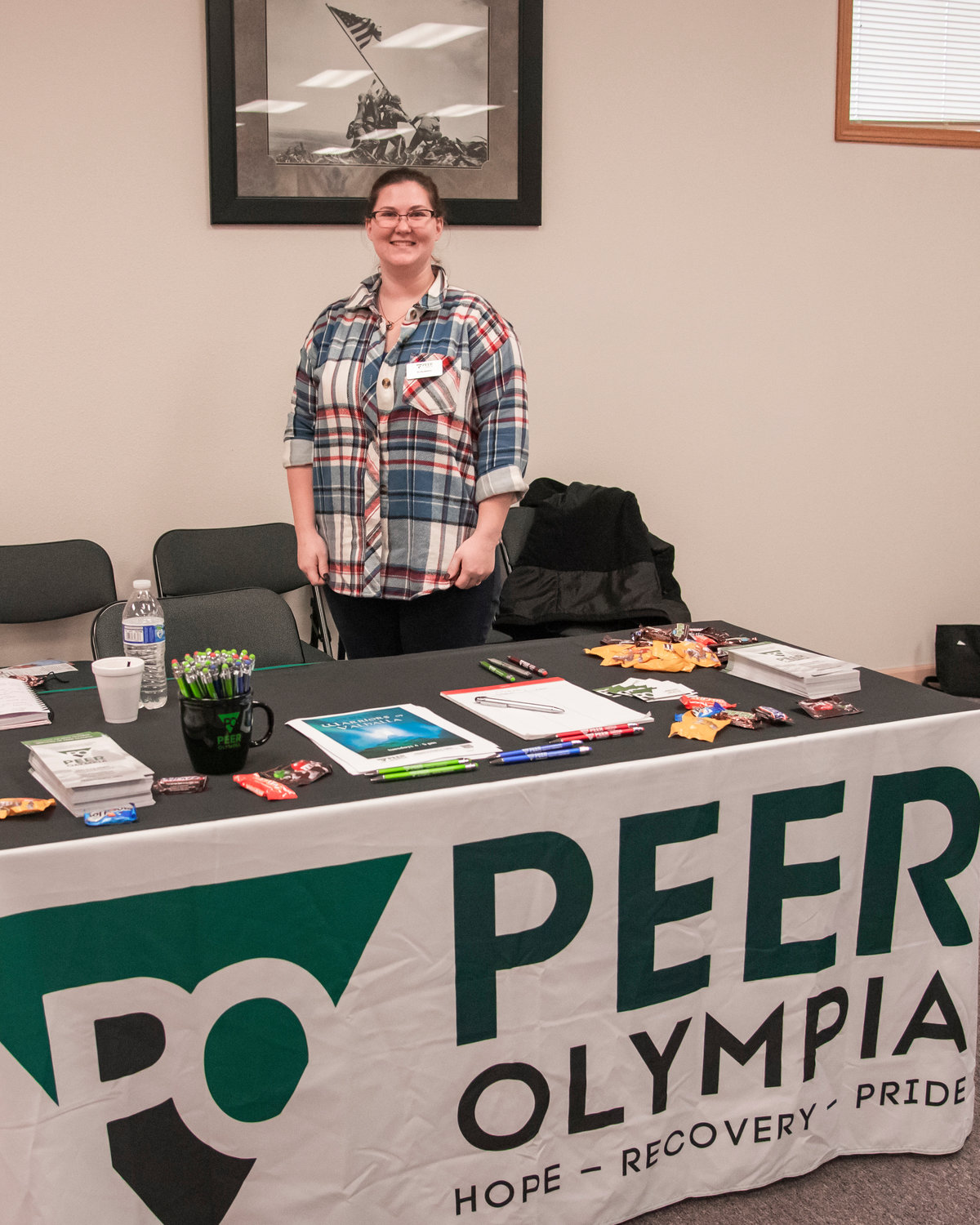 Kristi Lloyd, a volunteer with Peer Olympia smiles and stands at a booth in the Veterans Memorial Museum Thursday in Chehalis on Veterans Day.