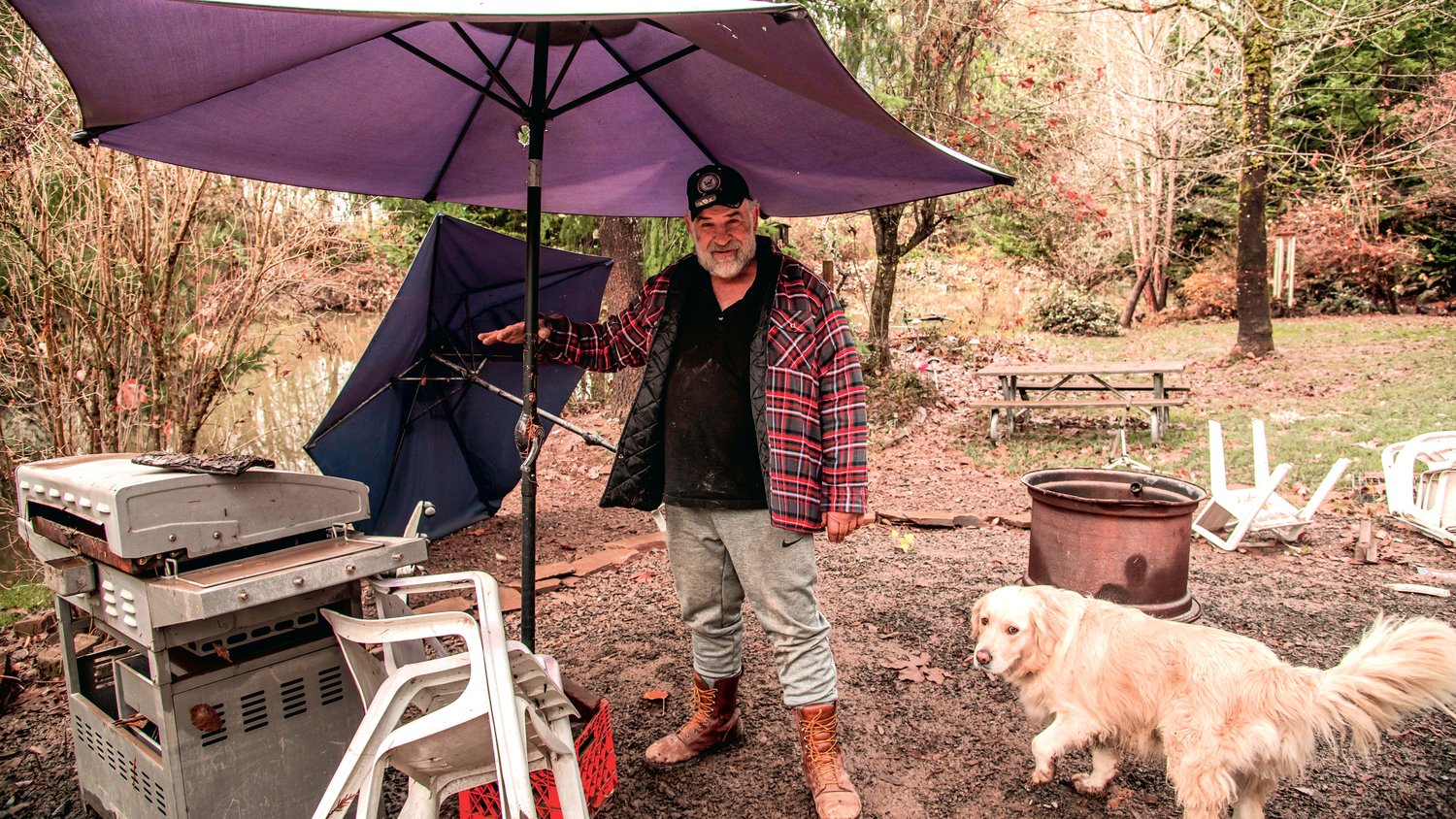 David Richter points out the height water rose to, on the pole of an umbrella near the river, during flooding in Randle while standing next to his dog Bear Saturday morning.