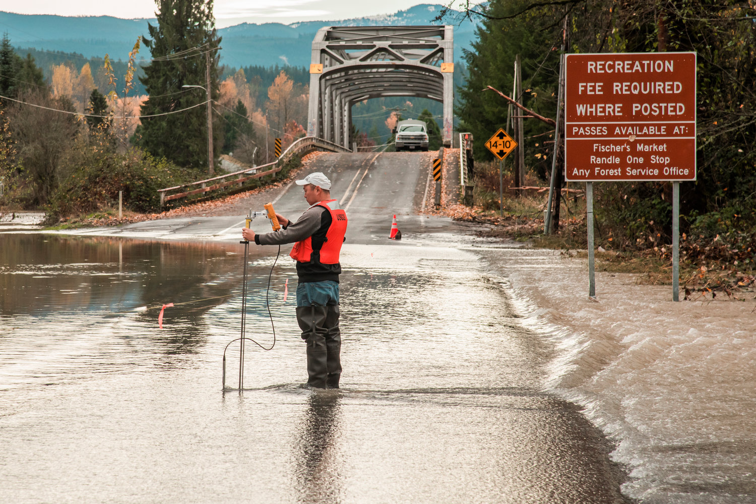 A United States Geological Survey member measures water flows as the Cowlitz River splashes over the roadway along Highway 131 in Randle on Saturday.