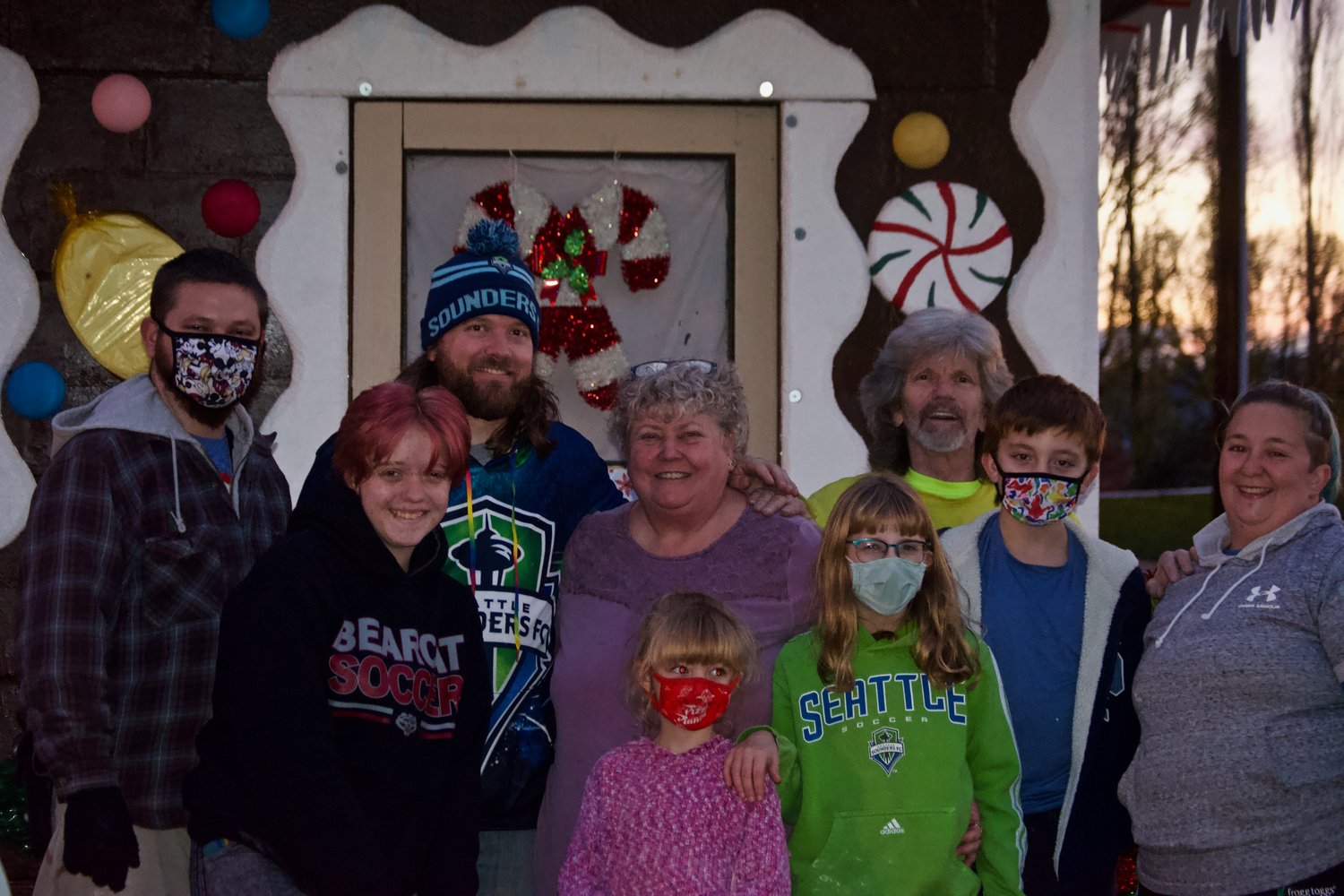 Chehalis City Councilor Terry Harris smiles with friends and family for a photo outside the gingerbread house in Chehalis on Saturday evening.