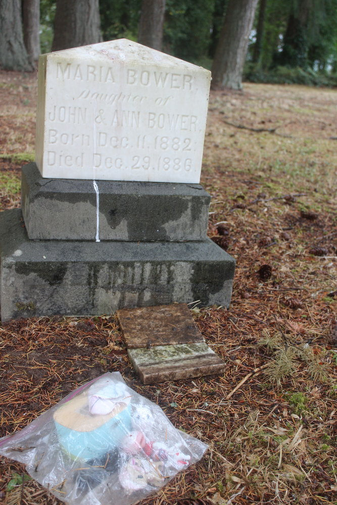 A bag of toys lays near the grave of Maria Bower, who is the earliest known burial at the Newaukum Hill Cemetery. Caretaker Mel Canfield said there are still family members of some of those interred there who visit the graves as well as community members who visit the space for its historic significance.