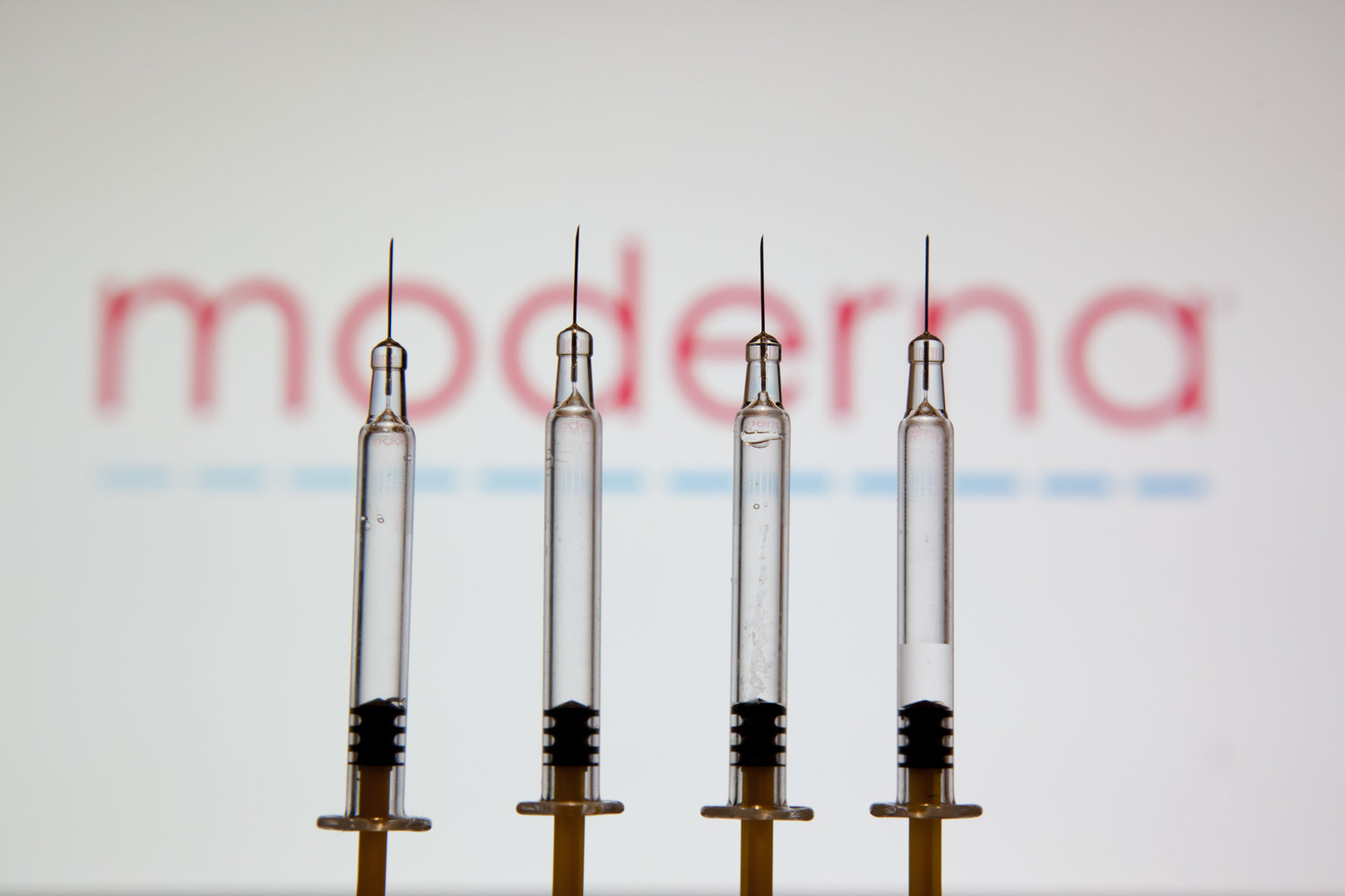 In a photo illustration, medical syringes seen displayed in front of the logo of pharmaceutical giant Moderna. (Konstantinos Zilos/SOPA Images/Zuma Press/TNS)
