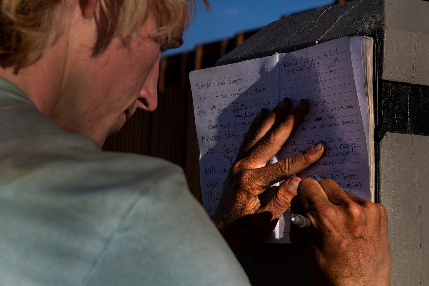 Stanford student Jackson Parell signs the Pacific Crest Trail log book as he reaches the Pacific Crest Trail Southern Terminus with hiking partner Sammy Potter at the Mexican border after a 12-day, 342-mile hike, on April 4, 2021, in Campo, California. (Gina Ferazzi/Los Angeles Times/TNS)