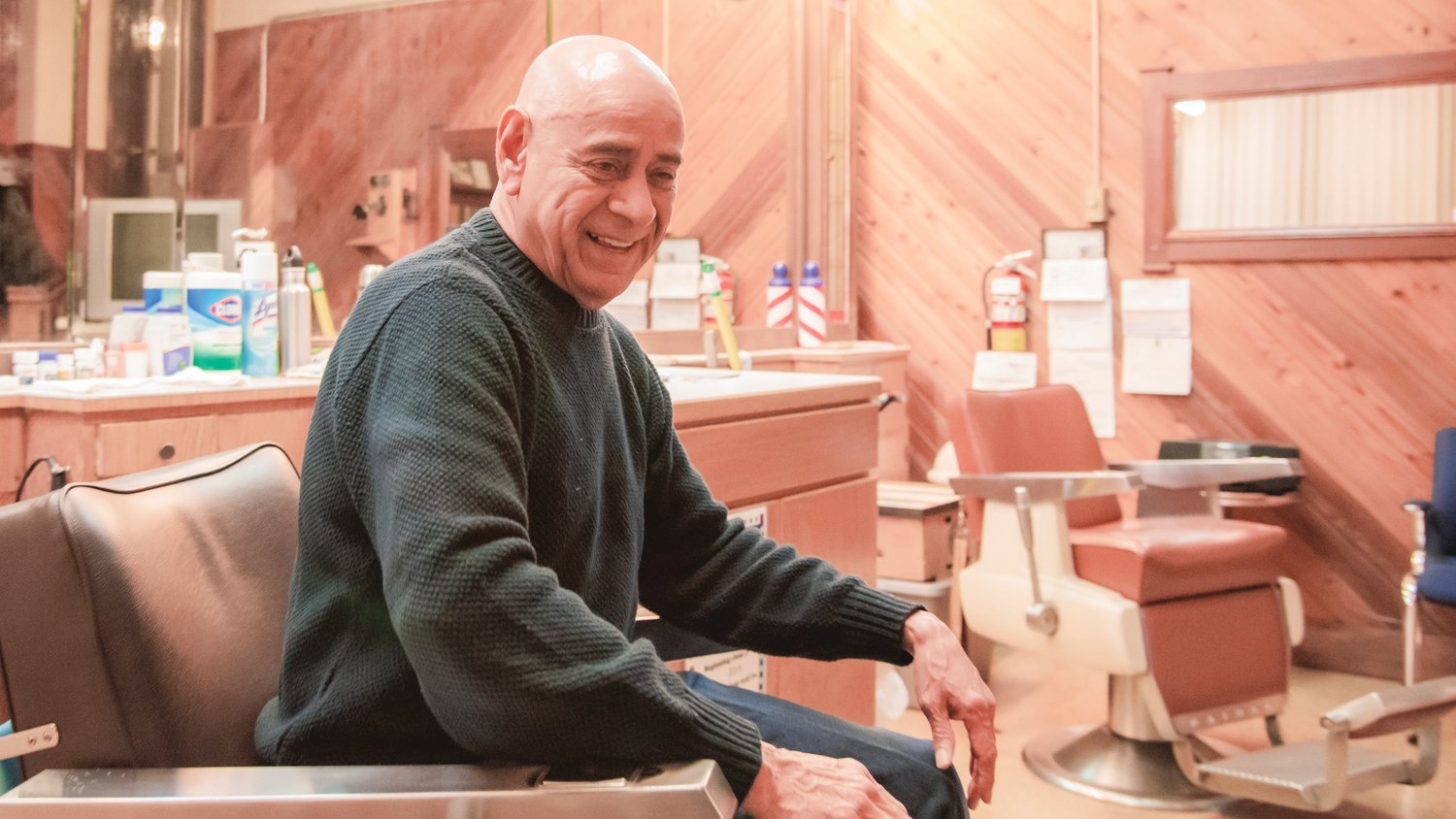 Roger Gonzales smiles while sitting in a chair inside his barber shop talking about people he has met through the years cutting hair in Lewis County.