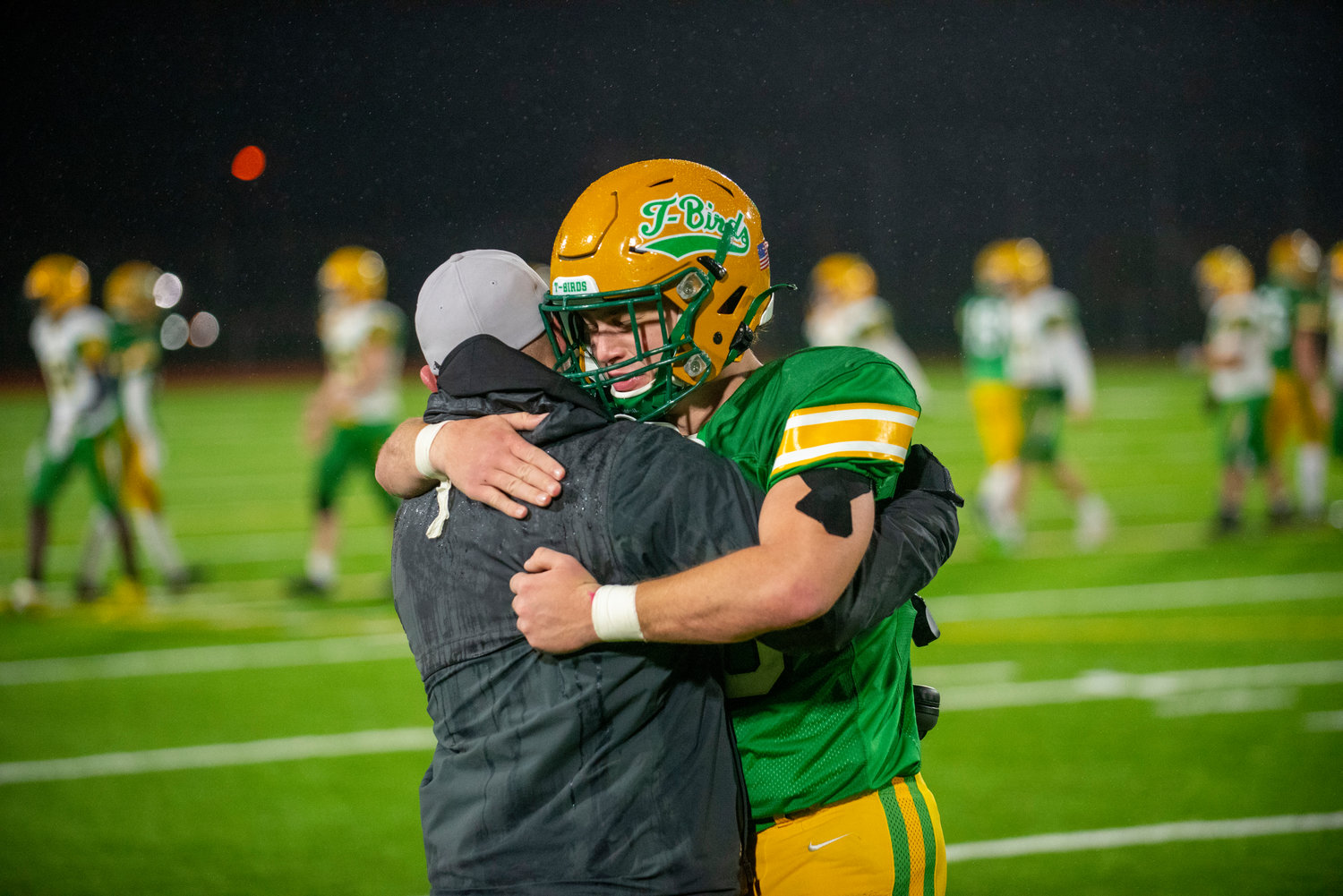 Tumwater senior Bennett Ferris hugs an assistant coach after the Thunderbirds fell 21-7 to Lynden in the 2A state football championship on Dec. 4 in Puyallup.
