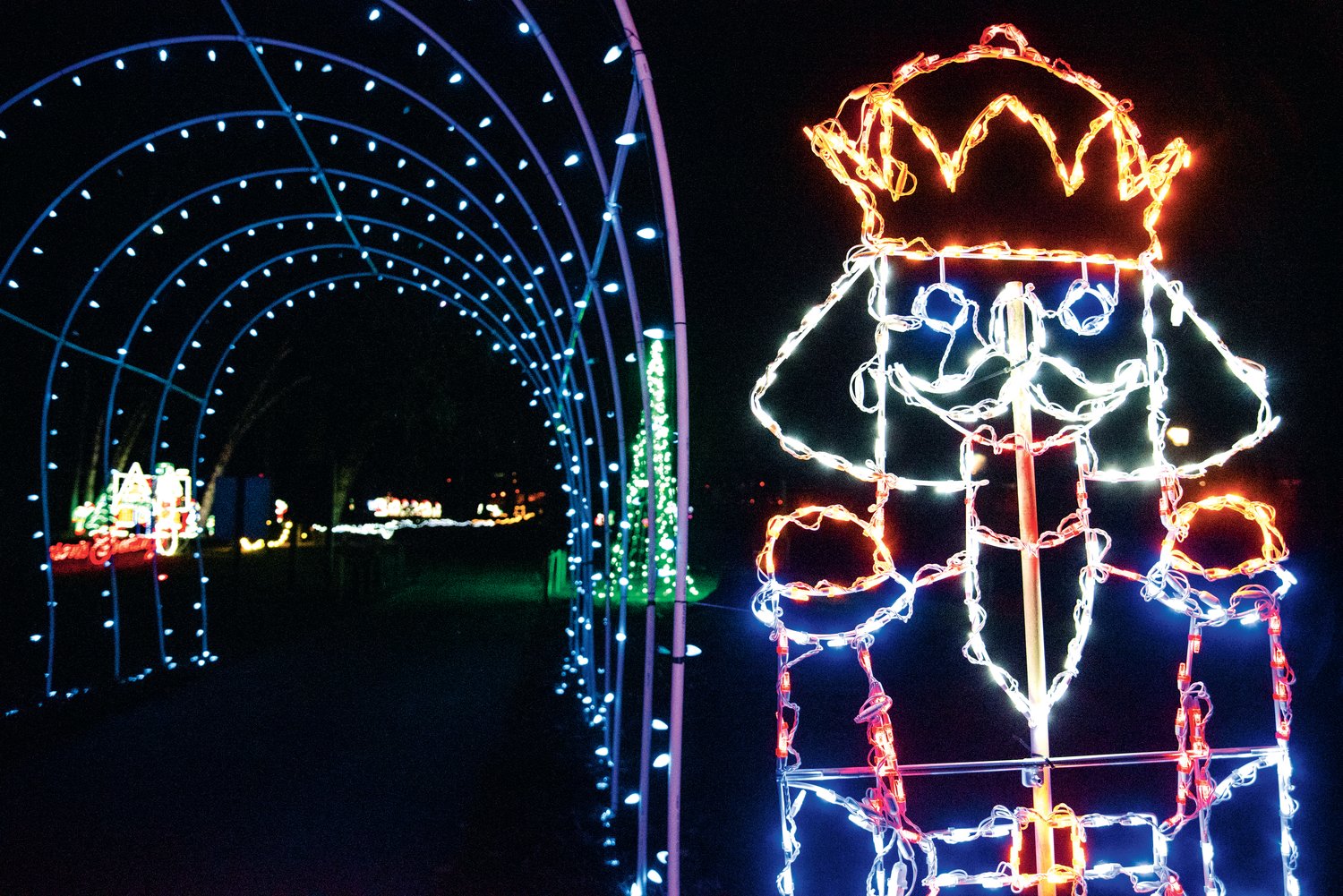 A nutcracker stands guard illuminated by Christmas lights near the entrance of a lighted tunnel at Borst Park in Centralia.