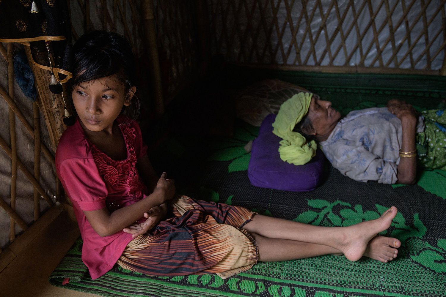 Rohingya refugee Saida Bibi (8, left) sits before her relative Bodu Zzaman (77, right), at the Kutupalong refugee camp near Cox's Bazar on Aug. 11, 2018. - According to her daughter, ZZaman, who is unable to talk, continues to suffer from a broken hip sustained when she fell fleeing bullets fired by Myanmar soldiers who attacked her village in September 2017. (Ed Jones/AFP via Getty Images/TNS)