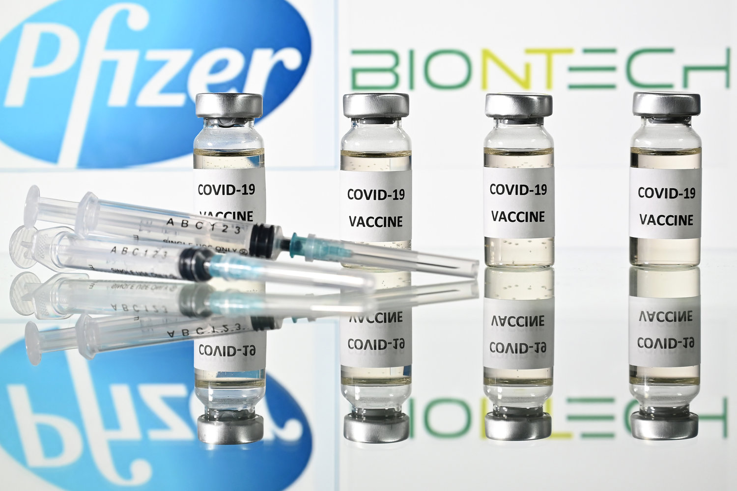 An illustration picture shows vials with Covid-19 Vaccine stickers attached and syringes with the logo of U.S. pharmaceutical company Pfizer and German partner BioNTech. (Justin Tallis/AFP/Getty Images/TNS)