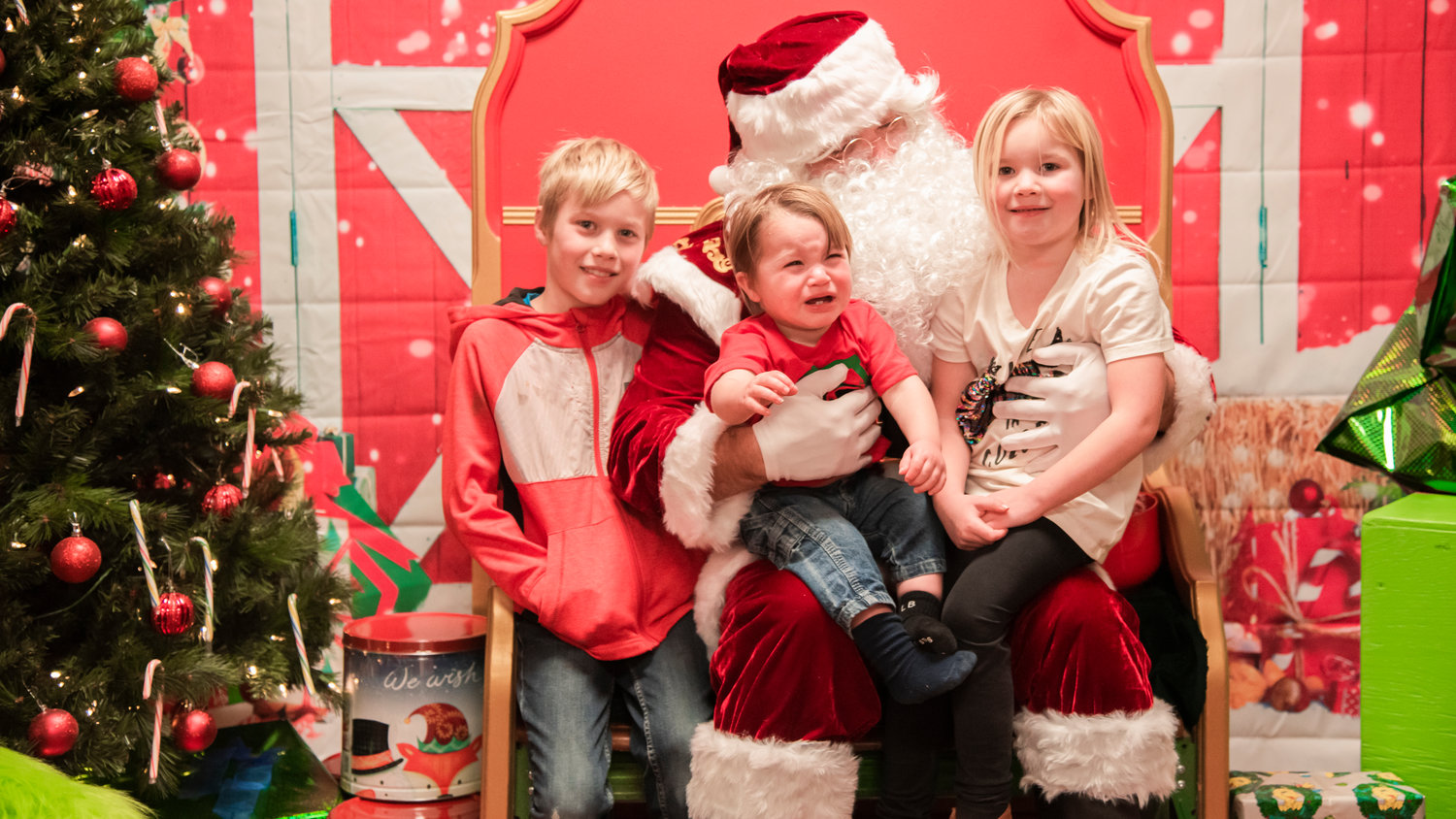 From left, Bradley, Jack, and Kinsley pose for a photo with Santa inside the Mossyrock Community Center during a tree lighting ceremony and gift raffle Saturday night.