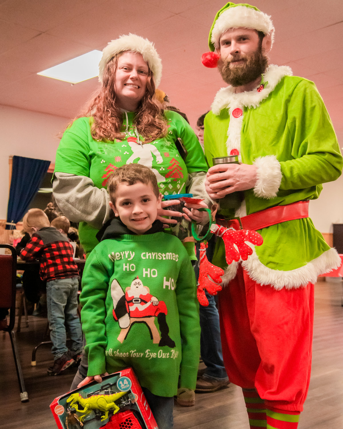Kayson, 5, smiles and poses for a photo with his parents Kelsey and Chris Hermann while sporting Christmas attire inside the Mossyrock Community Center Saturday night during a tree lighting ceremony.