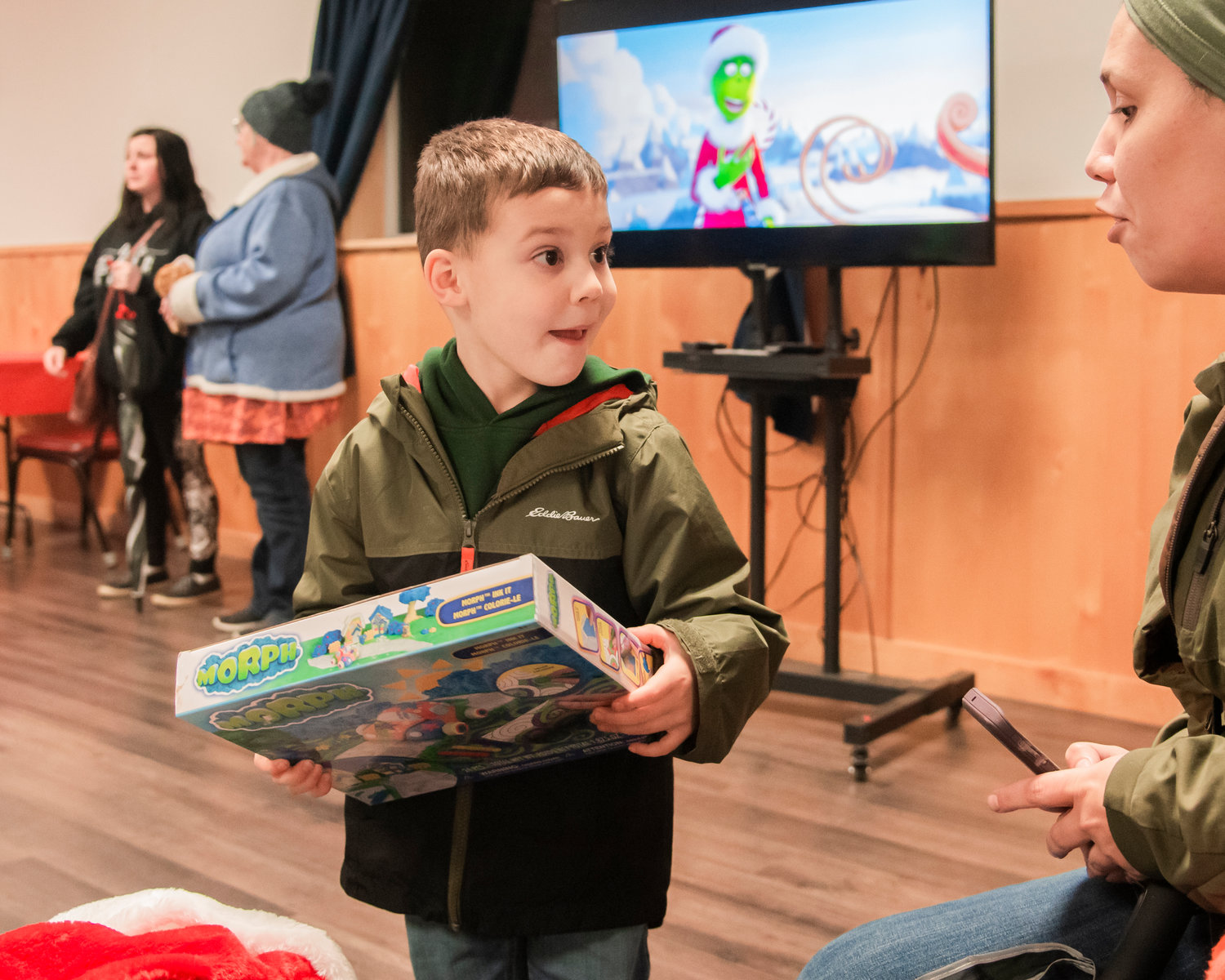 Clayton, 4, holds up his prize at the Mossyrock Community Center during a tree lighting ceremony and gift raffle Saturday night as Dr. Suess’ the Grinch animated movie plays in the background.