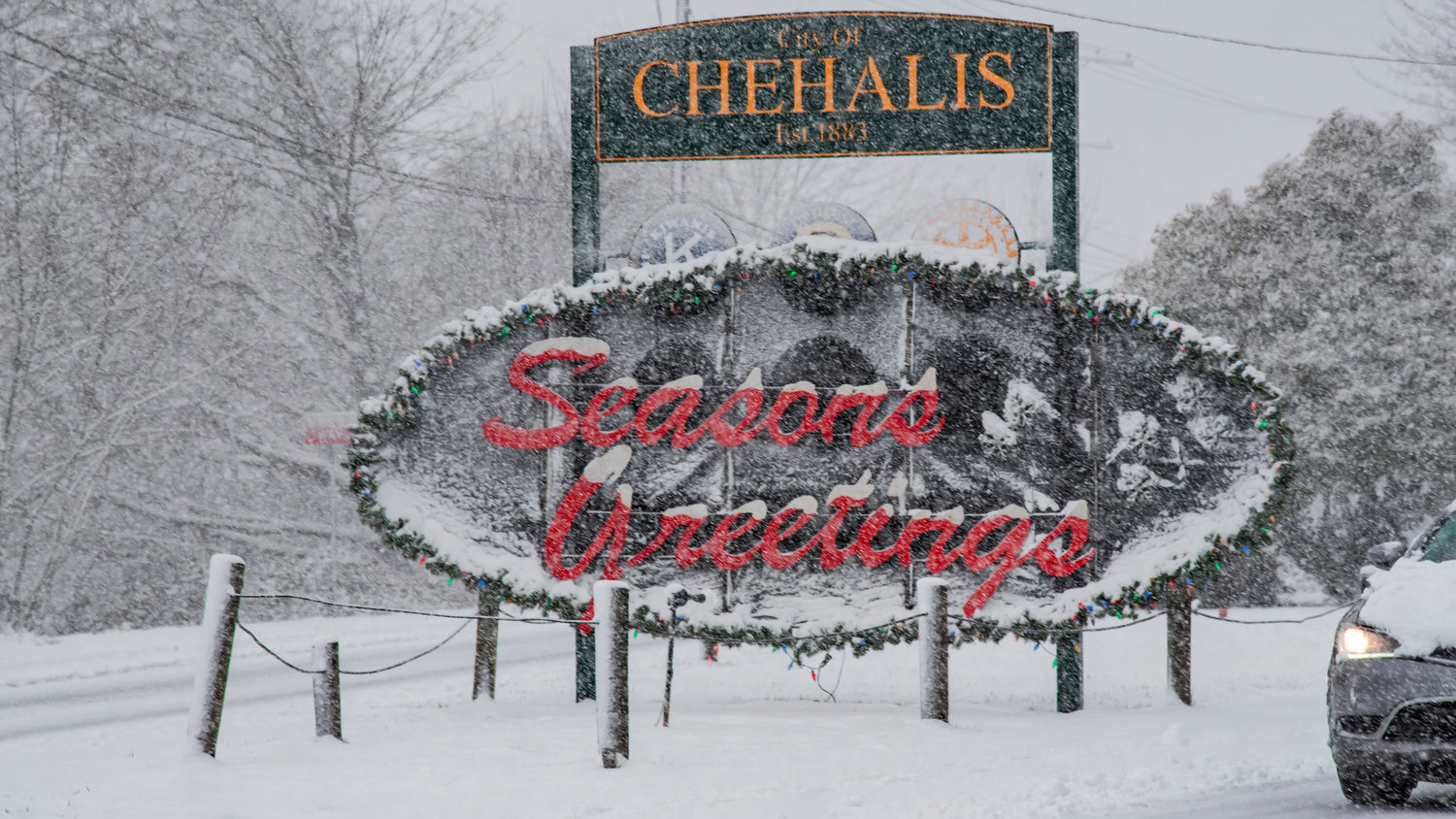 A sign reads “Seasons Greetings,” in Chehalis as snow falls Sunday afternoon.