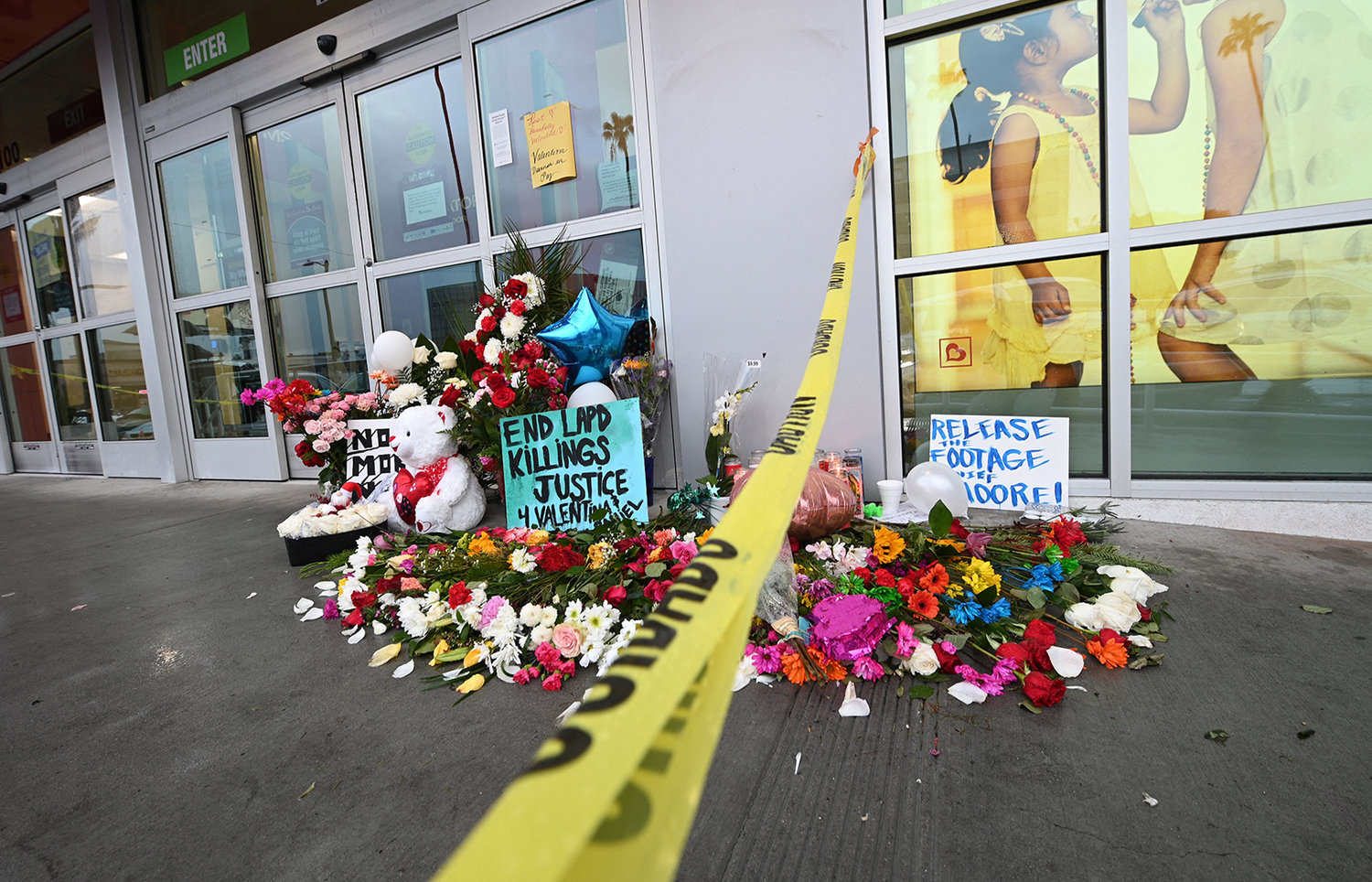 Flowers and baloons are left along a sign reading "Release the Footage Moore" at a makeshift memorial for the teenage girl who was killed by a police stray bullet at a Burlington coat factory in North Hollywood, California, Dec. 27, 2021. (Robyn Beck/AFP via Getty Images/TNS)