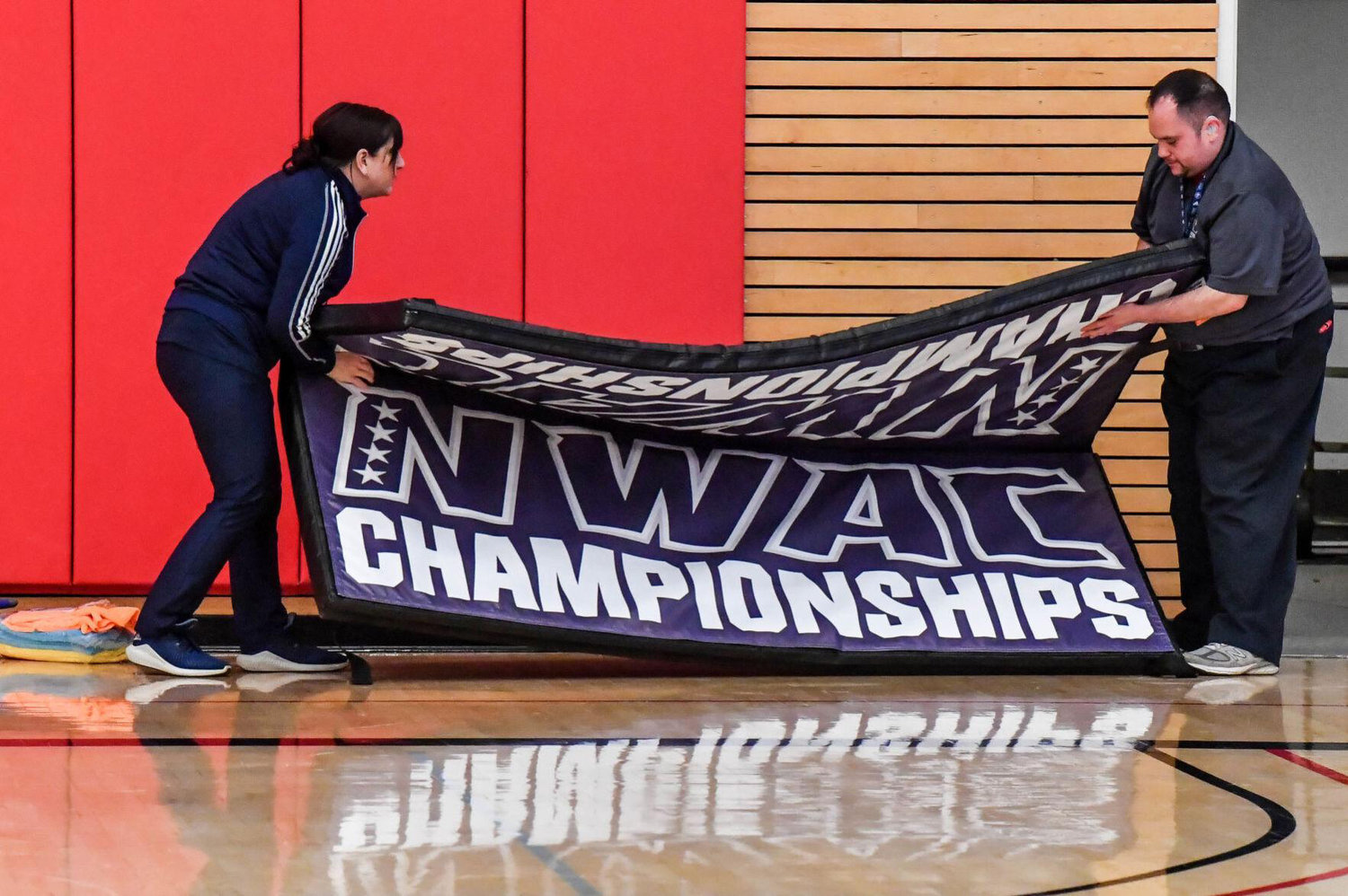 Northwest Athletic Conference staff fold up a sign following the basketball championships mid-tournament cancellation due to the coronavirus pandemic at Everett Community College on March 5, 2021.