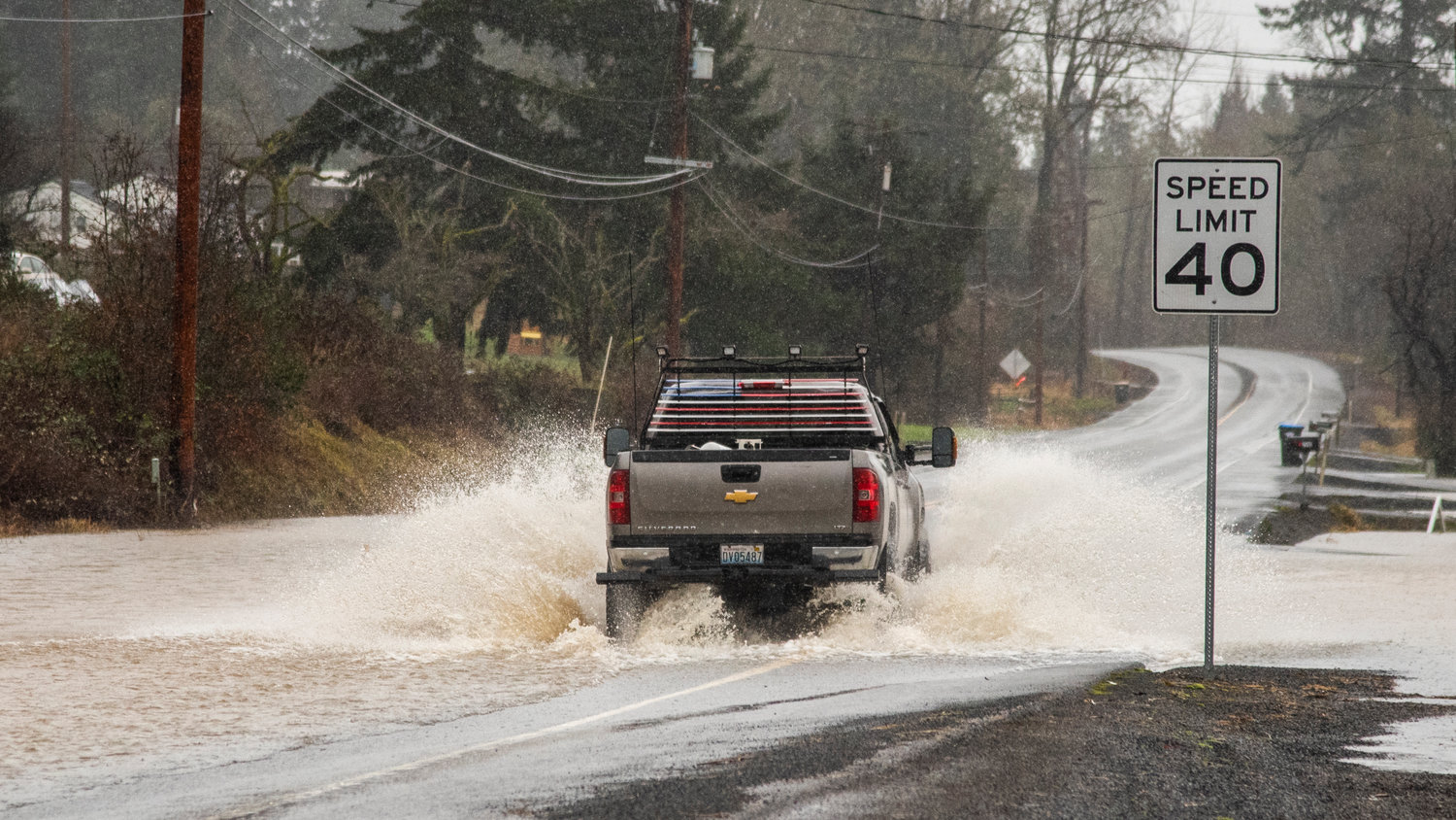 A truck drives down Jackson Highway in Chehalis as water flows over the roadway.