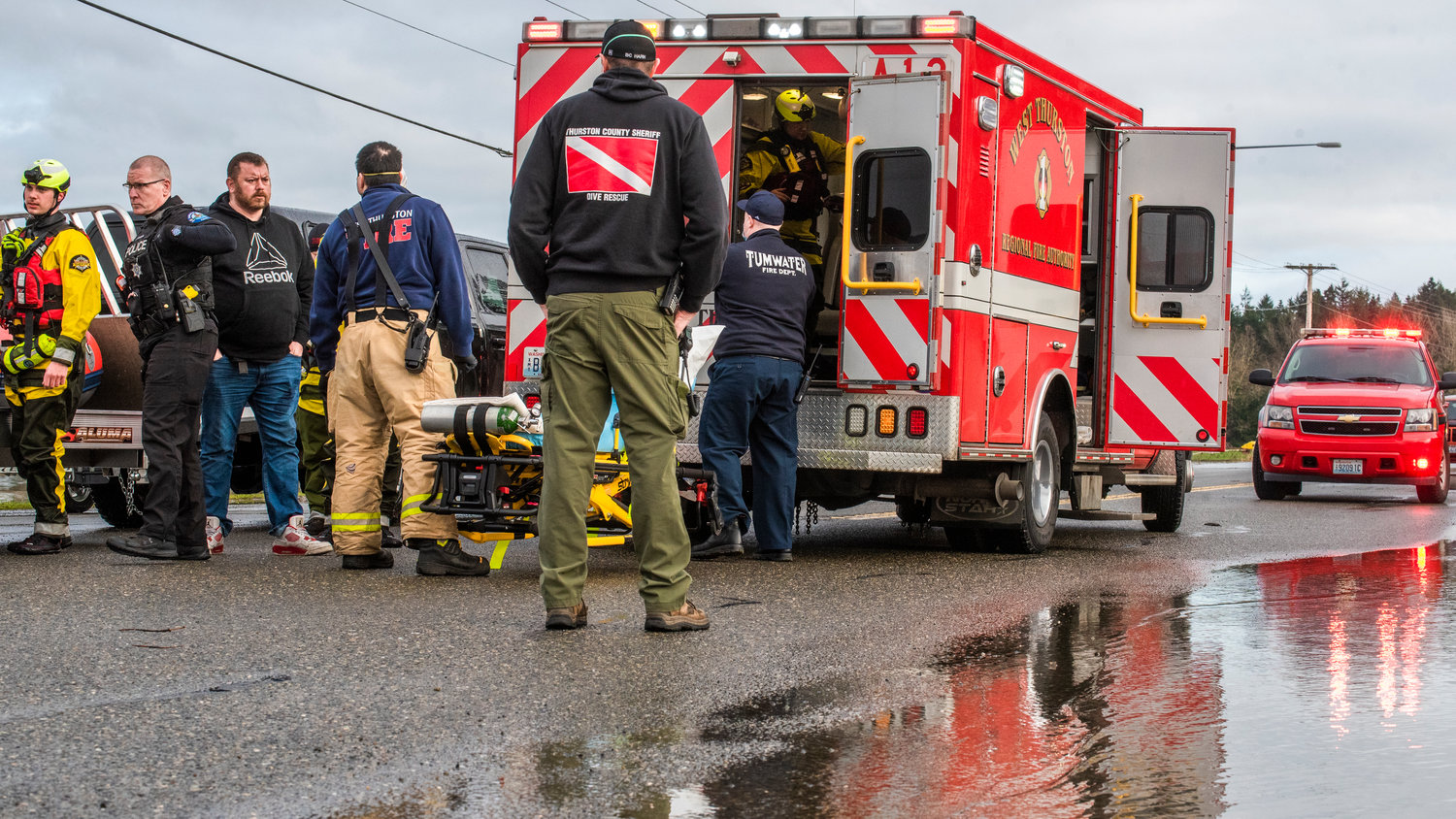 West Thurston Fire crews evaluate a crash victim with a head injury at the Moon Road intersection to U.S. Highway 12 in Rochester before having them enter an aid unit on a gurney to be transported to Providence St. Peter Hospital in Olympia through road closures Saturday afternoon.