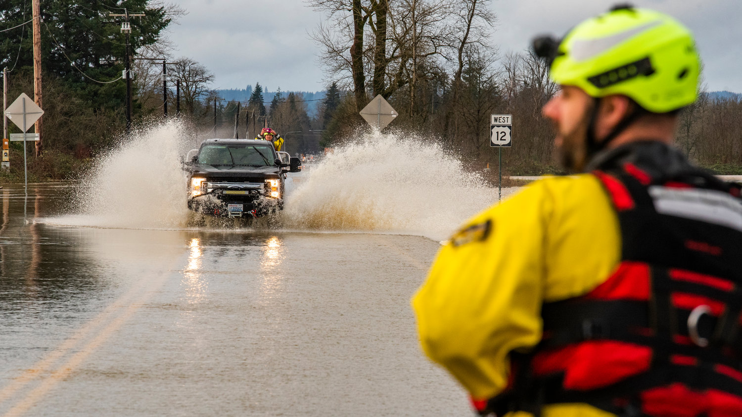 Rescue crews sit on standby at the Moon Road intersection to U.S. Highway 12 in Rochester as a unit transports a crash victim with a head injury across flood waters Saturday afternoon.