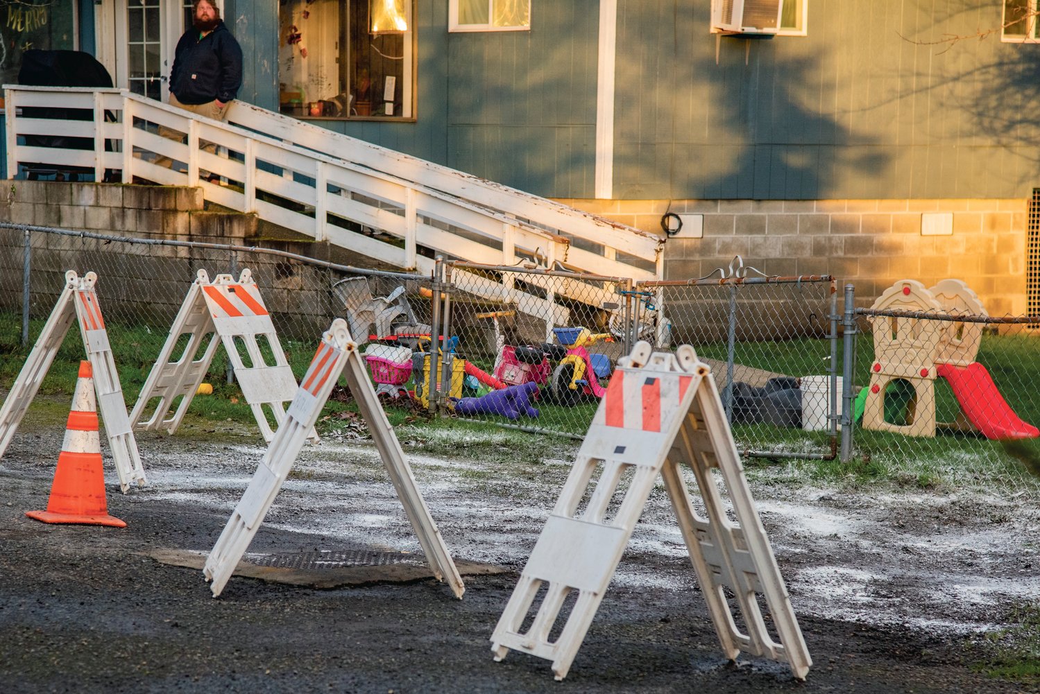 Seth Richards, 35, looks on from his porch where traffic cones and signs mark the area that flooded spilling into the yard he rents where his kids play.