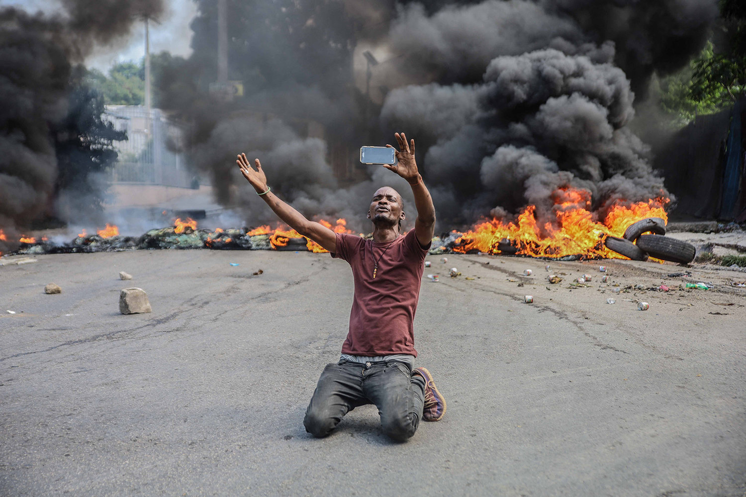 A man films himself in front of tires on fire during a general strike launched by several professional associations and companies to denounce insecurity in Port-au-Prince on Oct. 18, 2021. (Richard Pierrin/AFP via Getty Images/TNS)