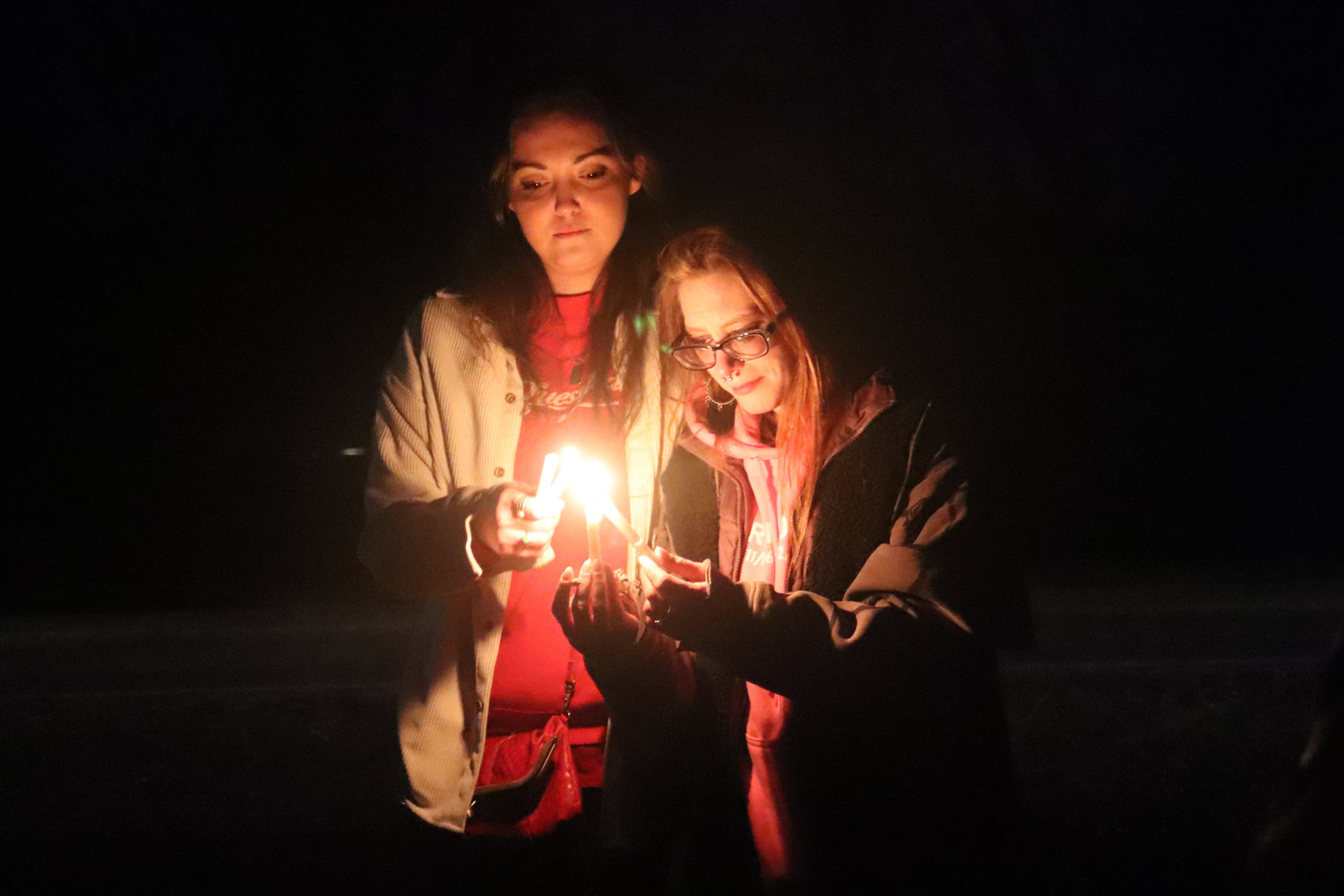 Sisters Karlee and Taylor Bodine share a tender moment at a vigil held on the 15th anniversary of the day their mother’s body was found on the side of Little Rock Road Southwest near Rochester.