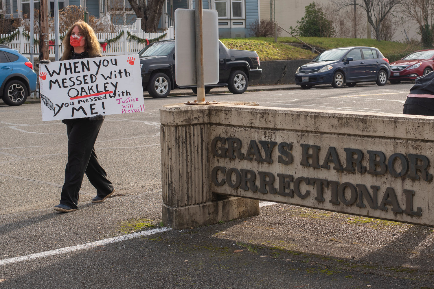 Cherie Roberts, Oakley’s foster grandmother, walks around the Grays Harbor County Correctional Facility holding a sign Saturday in Montesano.