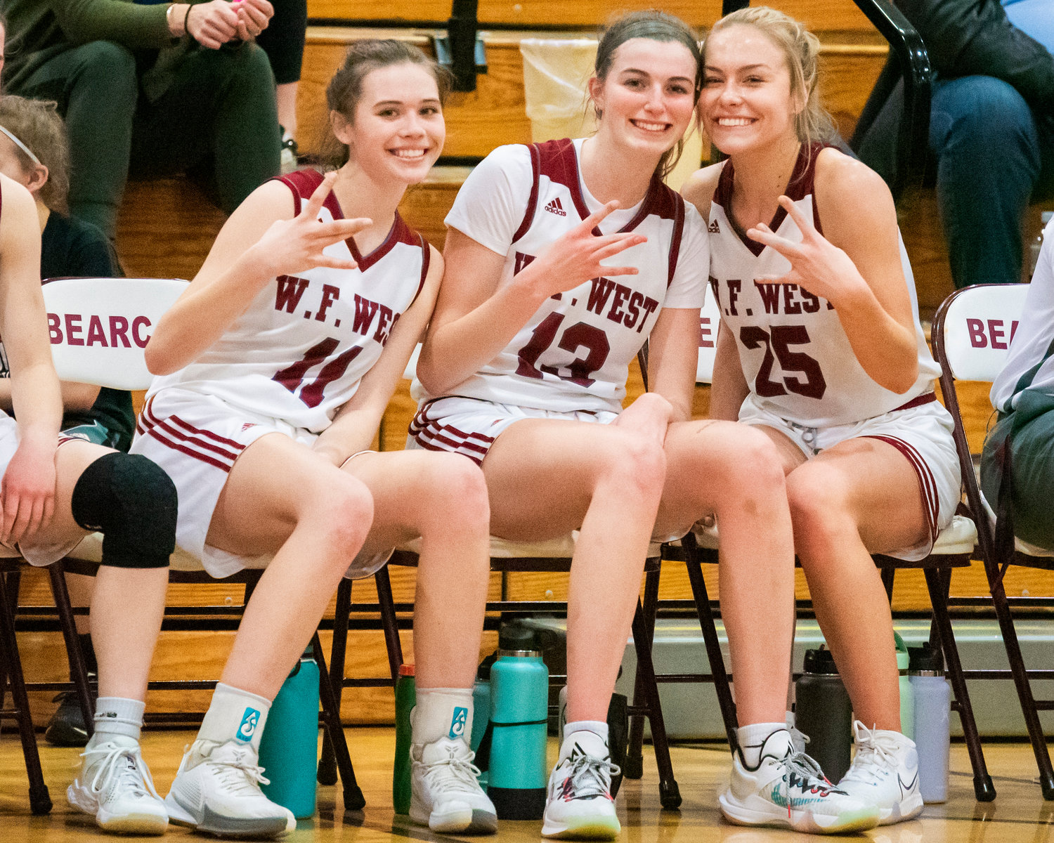 Bearcats Olivia Remund (11), Drea Brumfield (13), and Kayla Mccallum (25) throw their hands up smiling and pose Tuesday night at W.F. West High School.