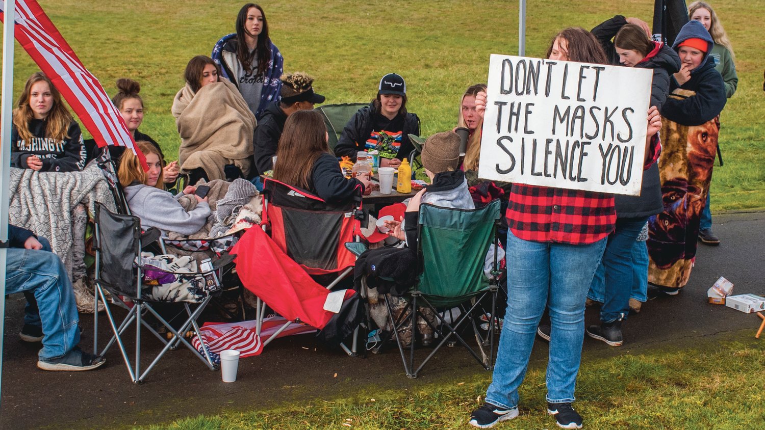 Pe Ell School District freshman Payon Endsley holds up a sign as students gather around food and a fire during a demonstration on Wednesday.