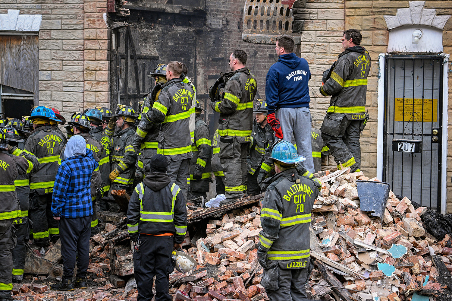 Baltimore City firefighters watch as the body of Lt. Paul Butrim is taken from the scene of a vacant row house fire on S. Stricker Street. Three firefighters died when they were trapped in a collapse while fighting the fire on Jan. 24. (Jerry Jackson/Baltimore Sun/TNS)