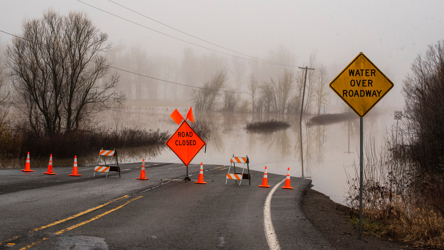 Signs and cones block a portion of Highway 131 near Randle as water flows over the roadway Tuesday morning.