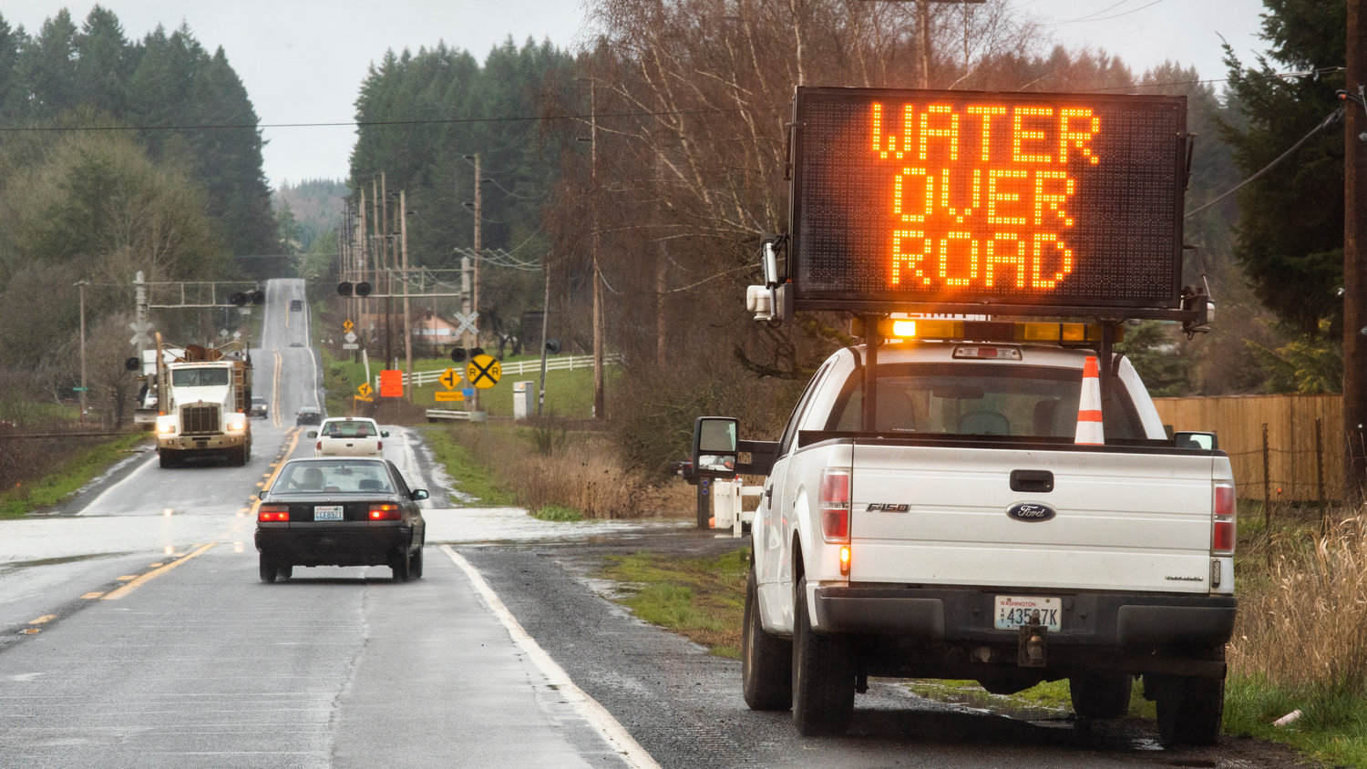 Vehicles slow as they approach a portion of Highway 6 where water flows over the roadway on Tuesday.