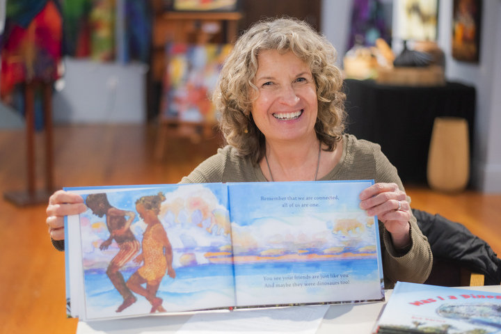 Sue Darius smiles while holding a copy of her book inside the Rectangle Gallery and Creative Space in downtown Centralia.