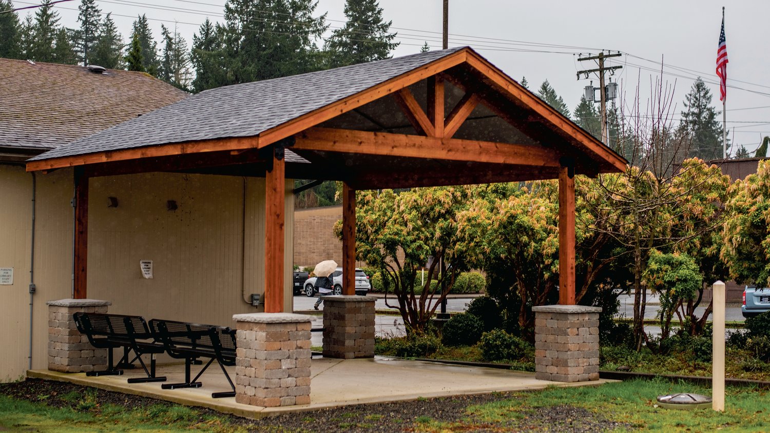 A man walks away with an umbrella in hand after stopping under a newly constructed pergola outside the Tenino Timberland Library to get out of the rain on Monday. In 2021, the city received a $26,414 grant to pave the city-owned parking lot behind the Sandstone Café, but because of the increasing costs of construction and product delays, the district switched the grant to build a visitor and community outdoor covered space next to the Tenino Timberland Library for those who visit the Tenino Farmers Market and visitors on the Yelm-Rainier-Tenino Trail to do things like read and eat lunch in.