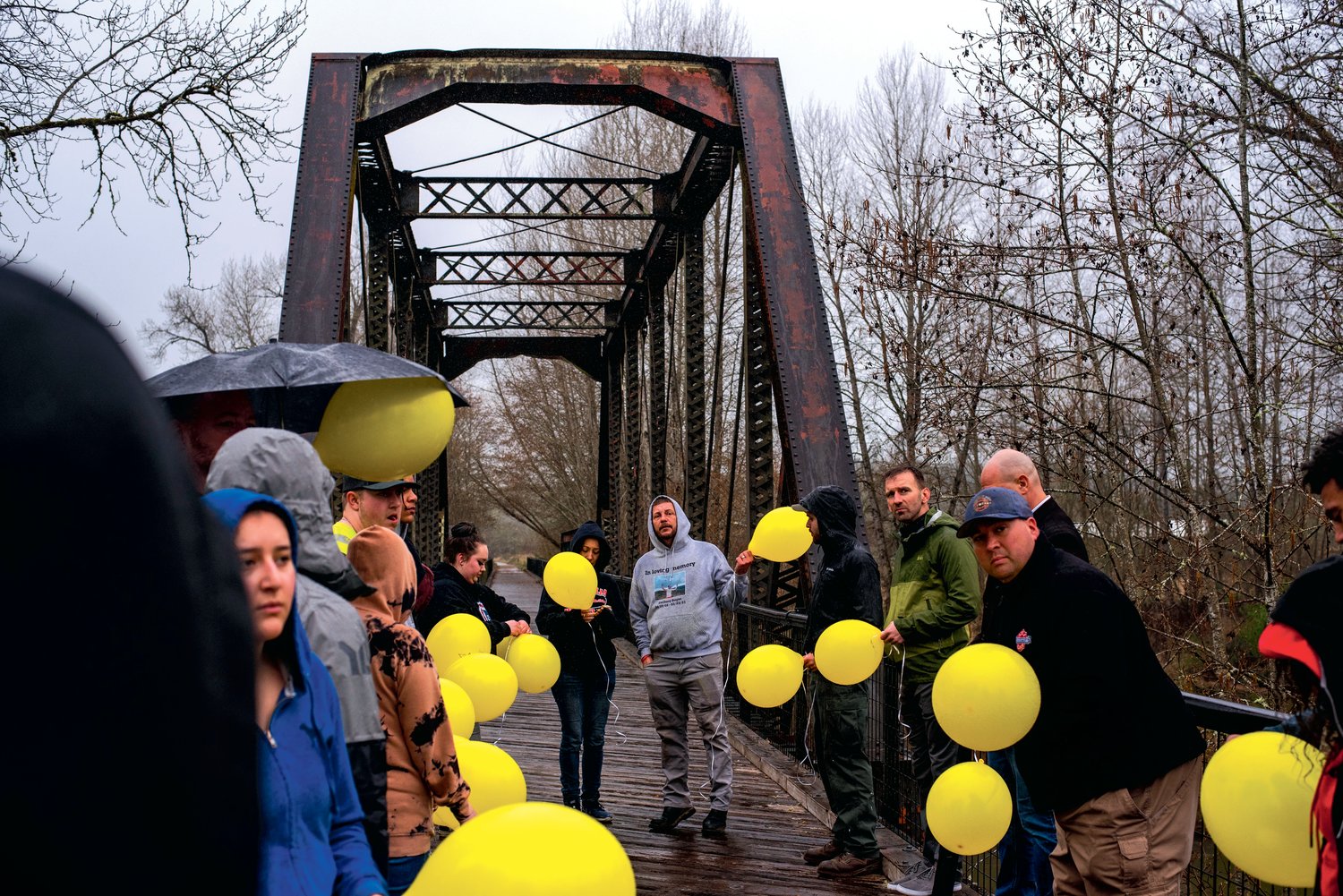 Family and friends hold balloons in the rain before releasing them into the air during an event marking one year since Zachary Rager lost his life.