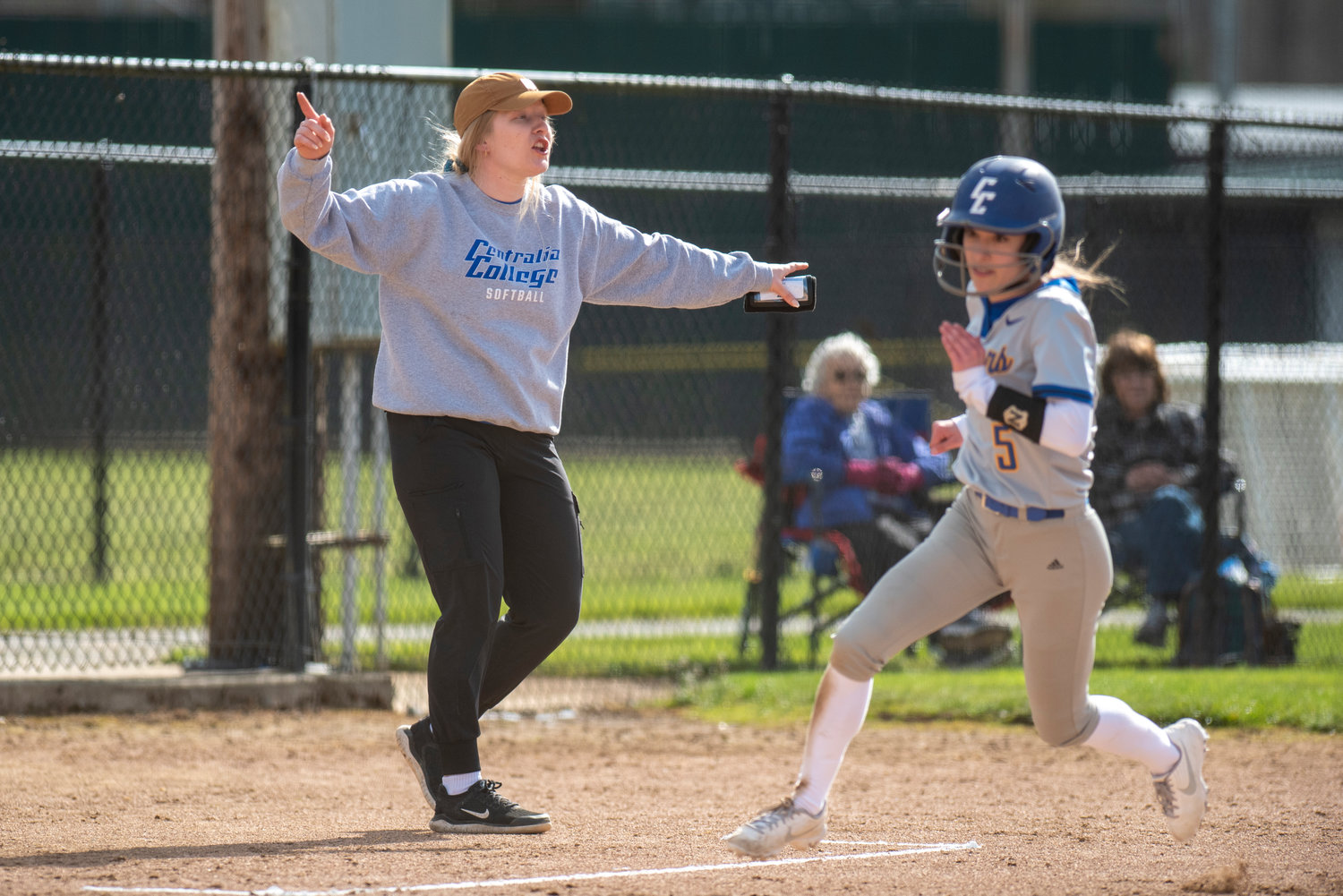 Centralia College softball coach Payton Pocklington waves Kylie Baker (5) home during a game against Chemeketa at home on March 25.