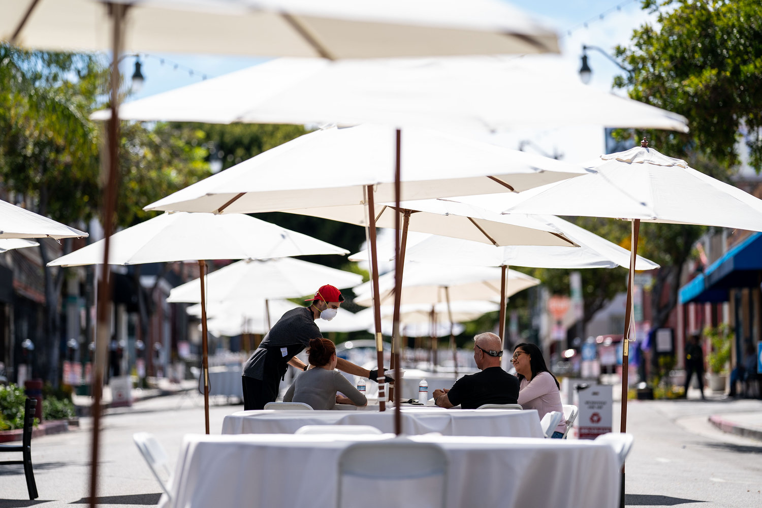 A restaurant worker serves food to people sitting at a table outside, on May 29, 2020, in San Pedro, California. (Kent Nishimura/Los Angeles Times/TNS)