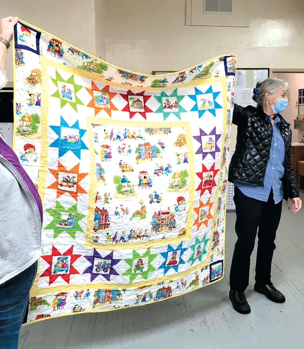 Members of the Prairie Points Quilt Guild display a finished quilt.