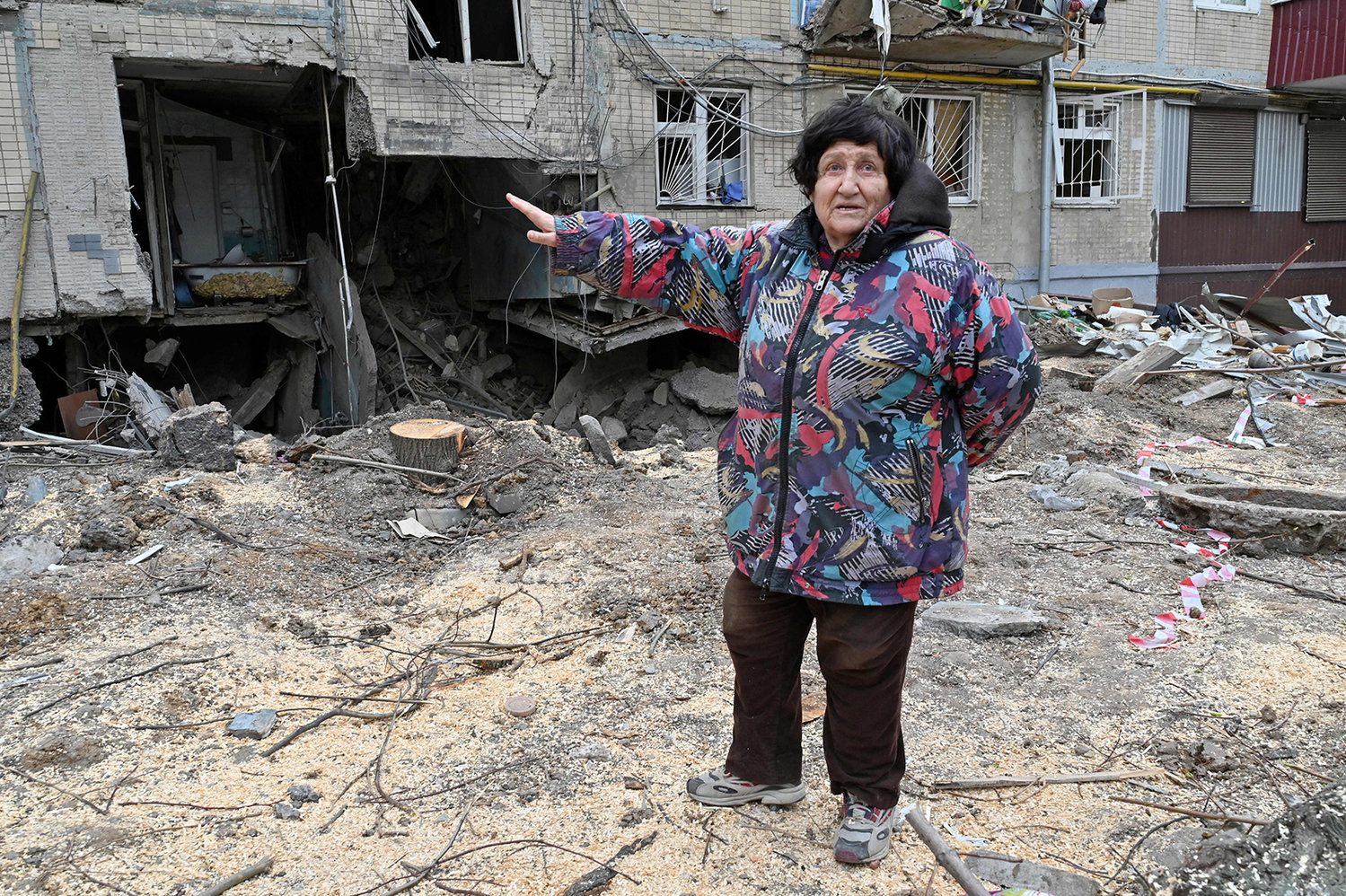 An elderly woman gestures toward a partially destroyed five-story building in the Ukrainian city of Kharkiv on April 10, 2022, amid the Russian invasion of Ukraine. (Sergey Bobok/AFP via Getty Images/TNS)